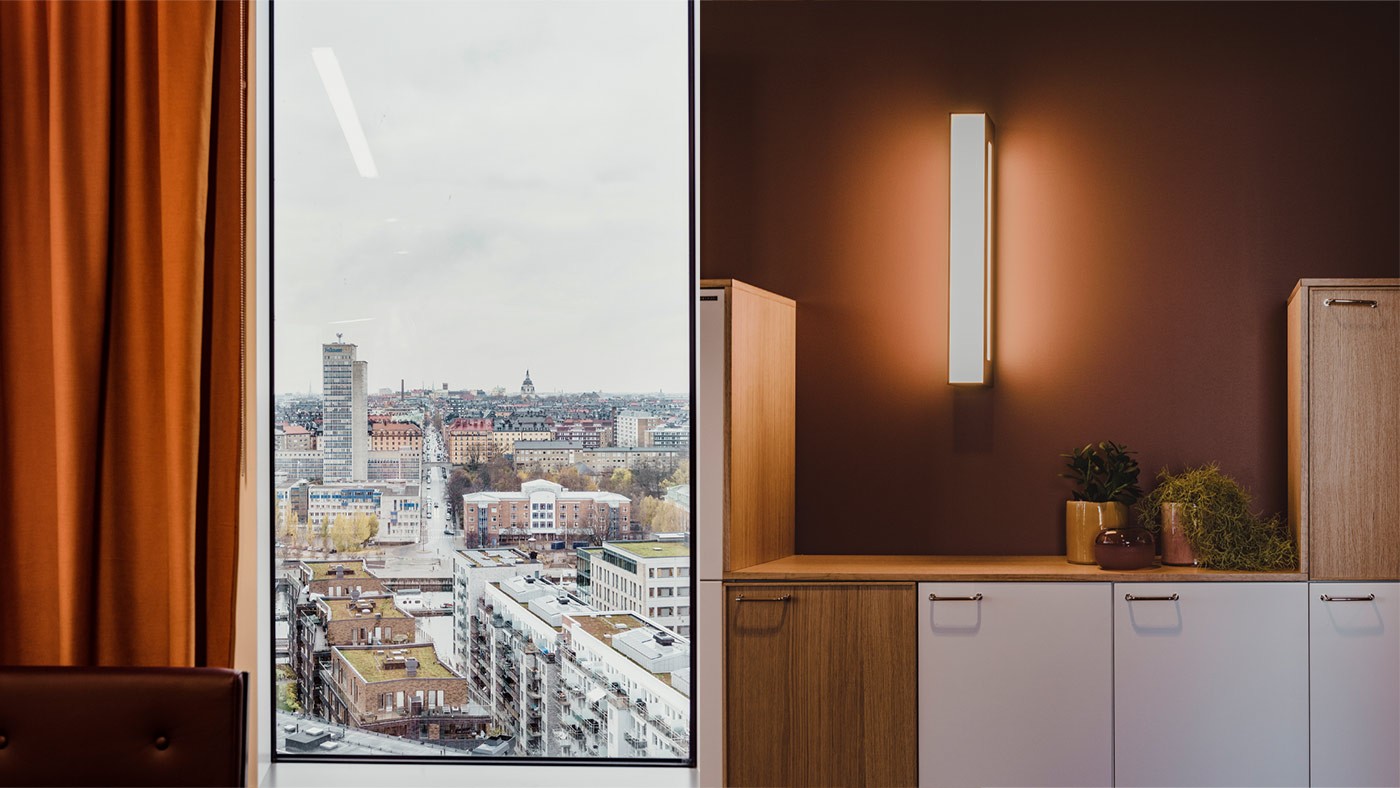 Modern kontorsinteriör med träskåp och ett stort fönster med utsikt över stadens byggnader.