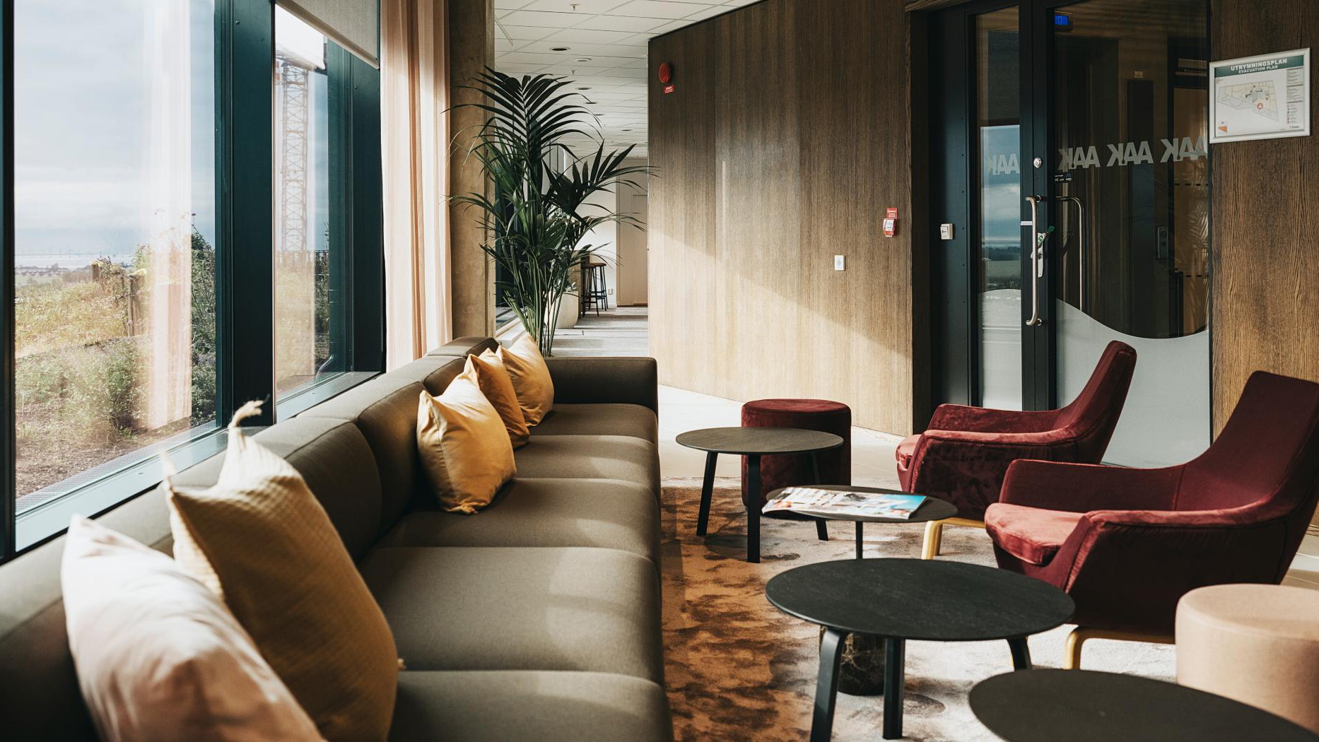 Modern, mysig lounge med stilfulla möbler och stora fönster Modern loungeområde med mjuka sittplatser, stilfull inredning och stora fönster med utsikt över en naturskön vy.