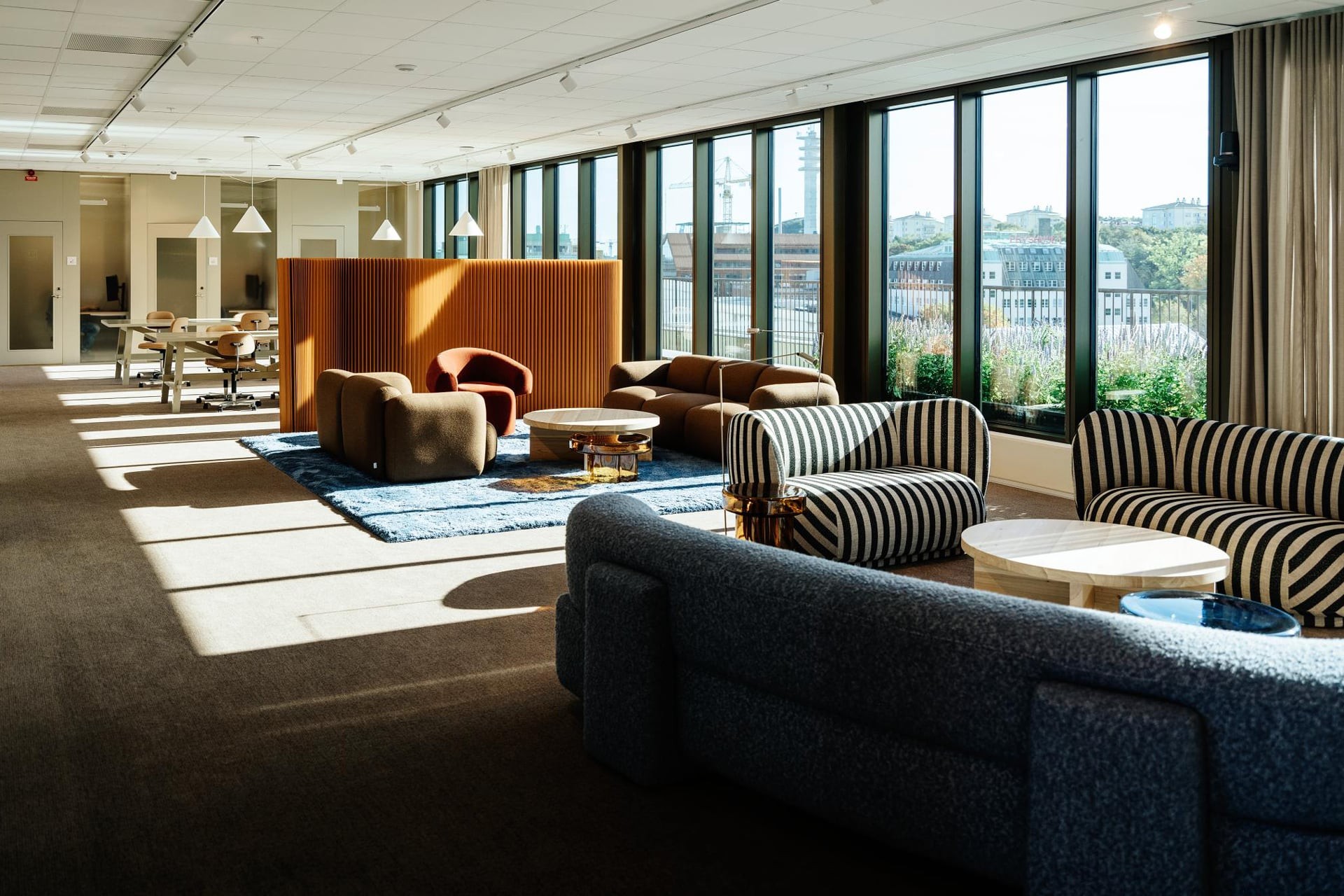 Modern kontorslounge med stiliga möbler och stora fönster Modern kontorslounge med stilfulla sittplatser, stora fönster och rikligt med naturligt ljus.