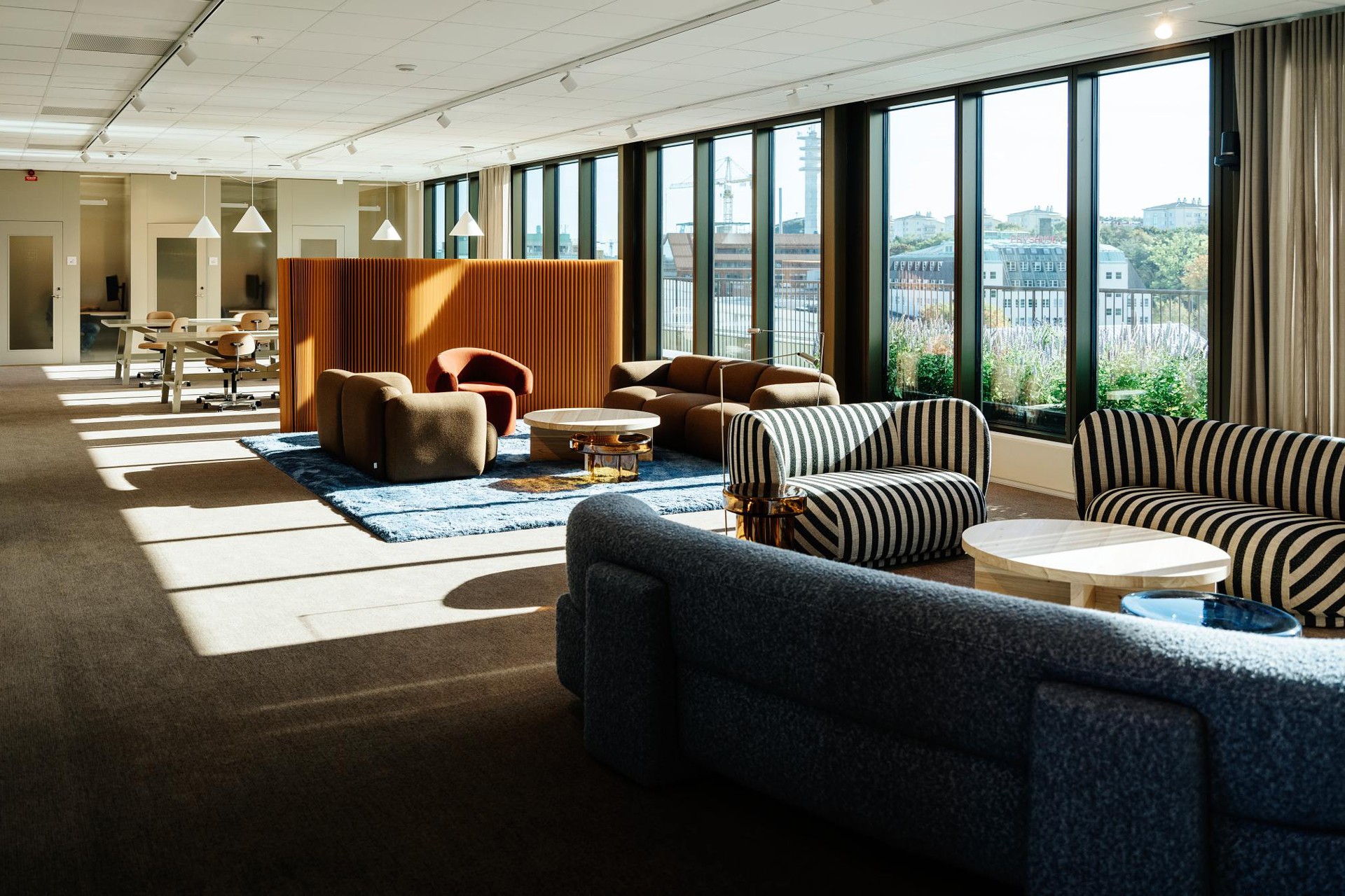 Modern kontorslounge med stiliga möbler och stora fönster Modern kontorslounge med stilfulla sittplatser, stora fönster och rikligt med naturligt ljus.