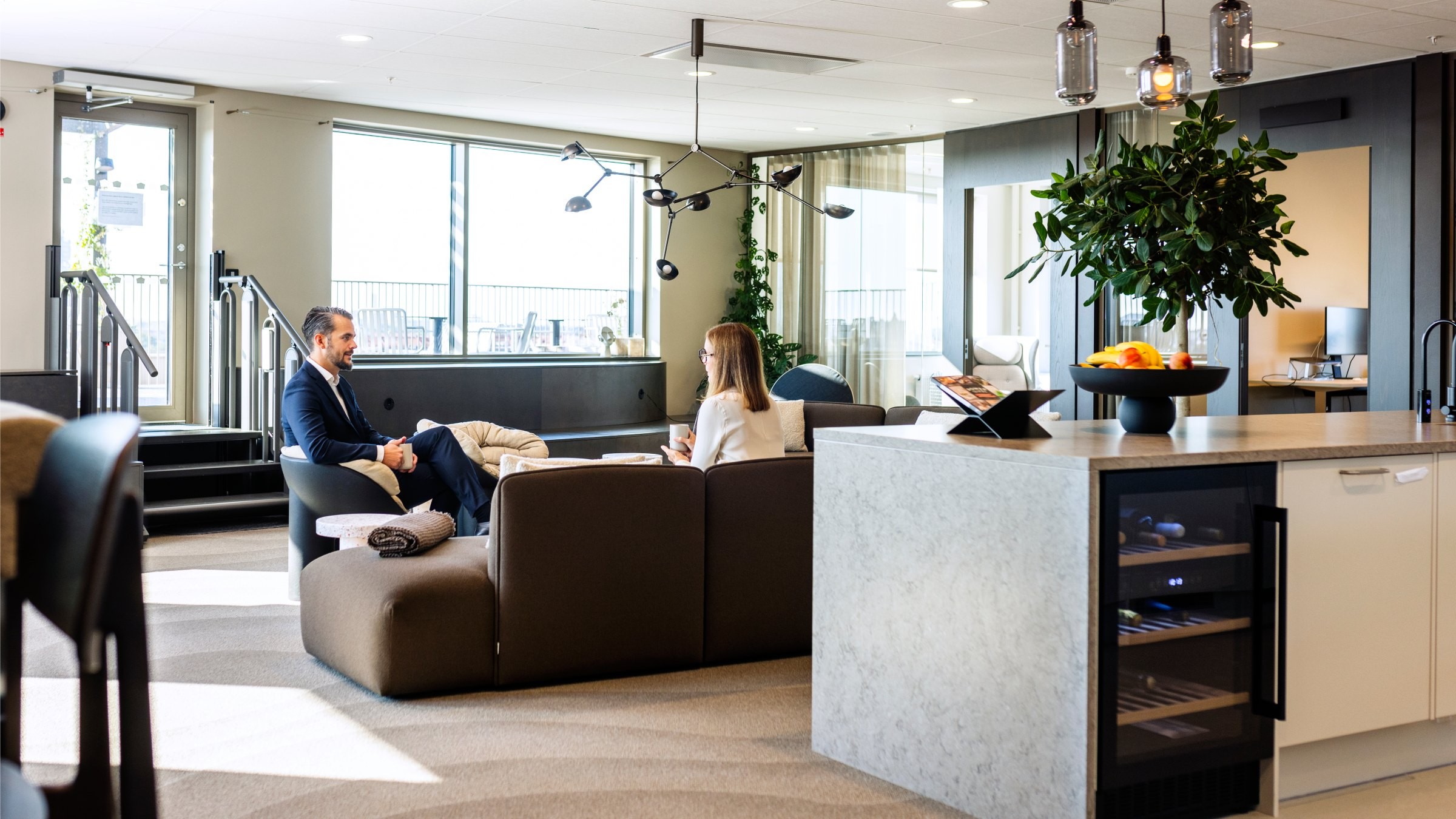 Modern kontorslounge med två yrkespersoner som har ett möte vid ett stort fönster.