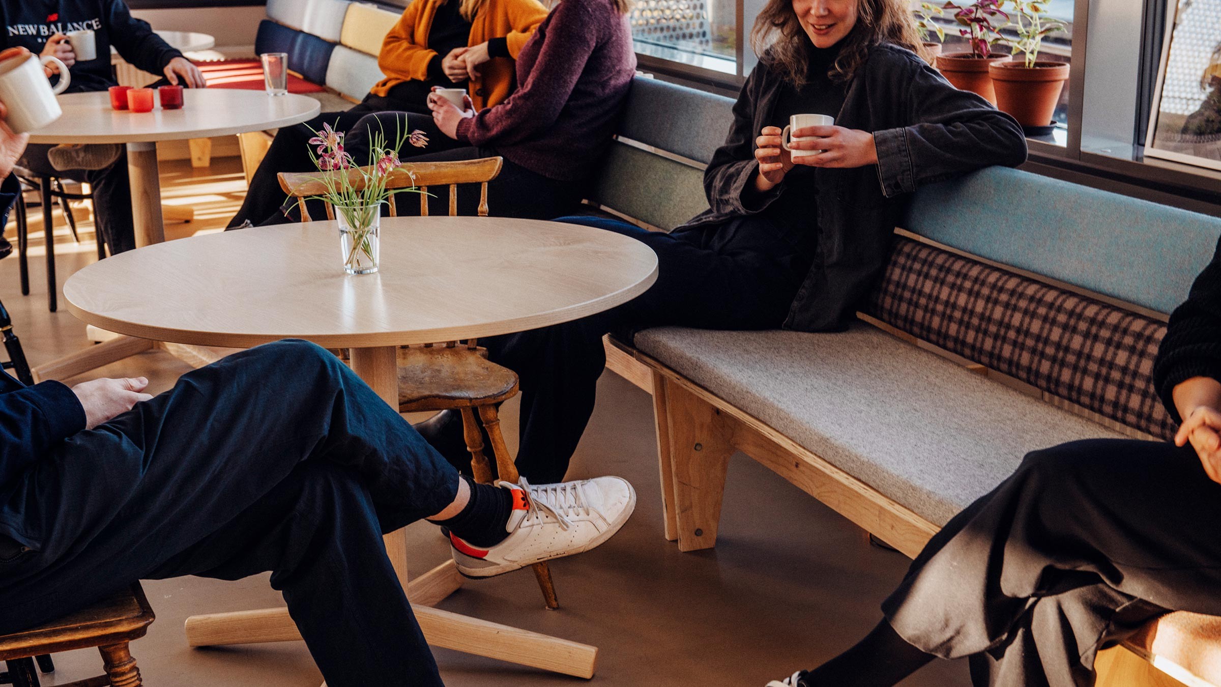 Casual Cafe Gathering: Friends Enjoying Coffee Together Group of people casually sitting and chatting around a table in a cozy café setting.
