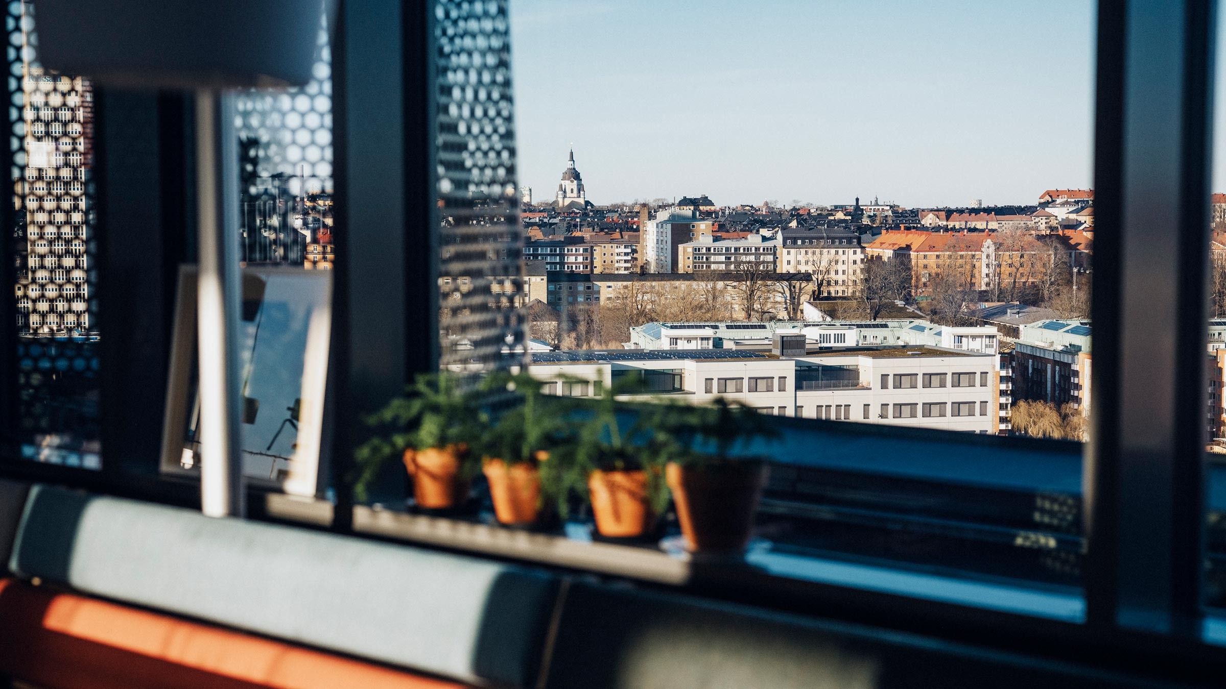 Stylish Office View Overlooking City Skyline with Plants Modern office interior with a cityscape view through large windows, featuring potted plants.