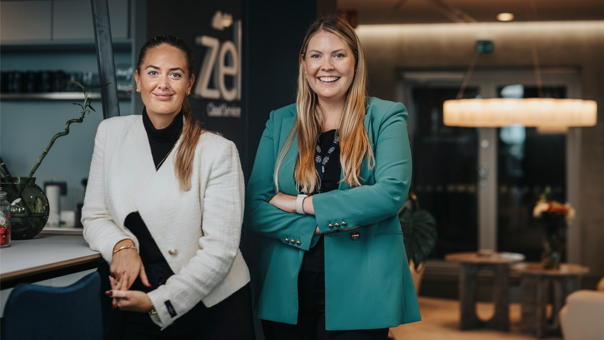 Professionella kvinnor i modern kontorsmiljö Två kvinnor i stiliga kavajer står i ett modernt kontorsutrymme med elegant inredning.