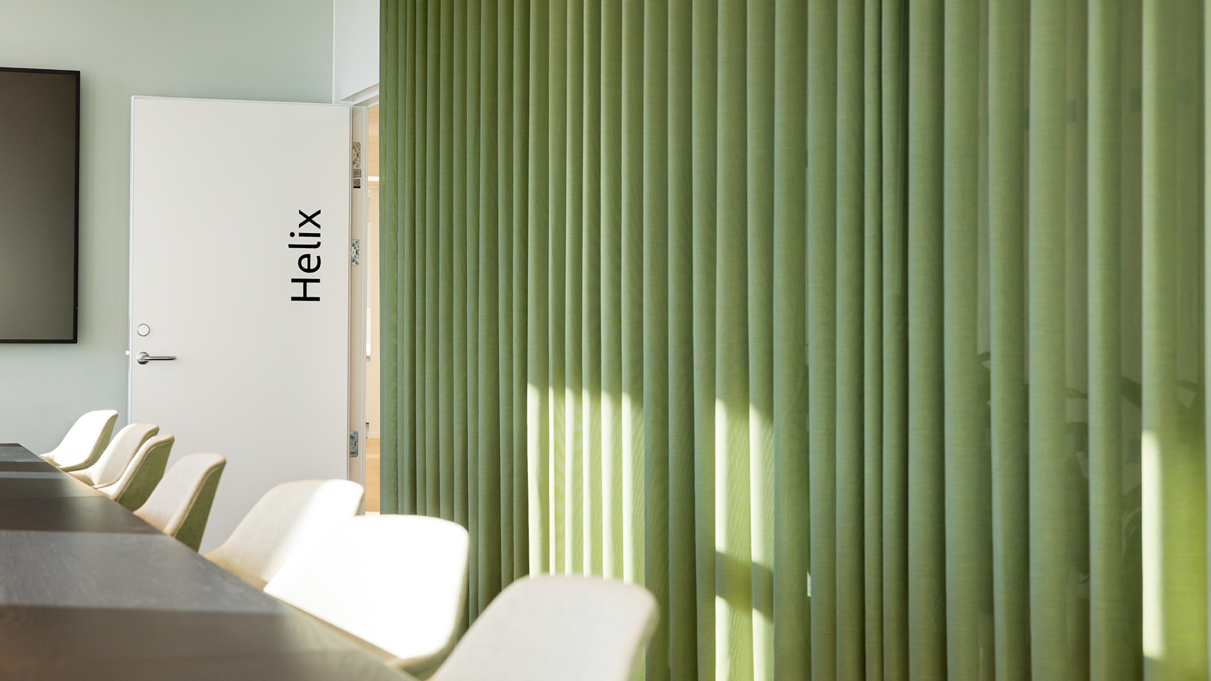 Modern konferensrum med gröna gardiner och Helix-dörr Modern konferensrum med gröna gardiner, beige stolar och en dörr märkt "Helix."