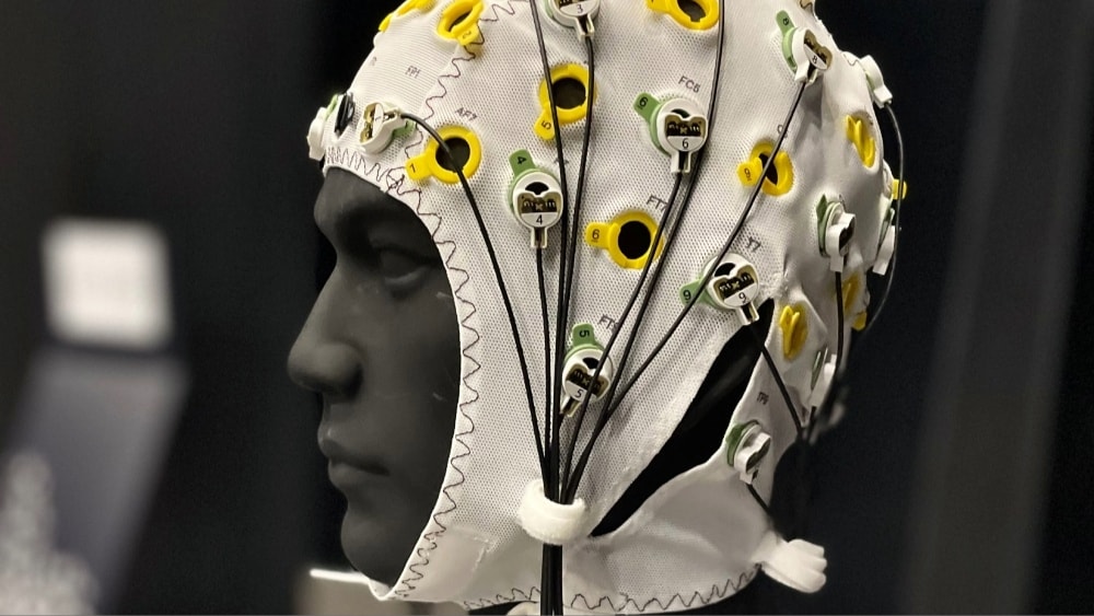 Vitt EEG-mössa med elektroder och ledningar används för övervakning av hjärnaktivitet på svart bakgrund.