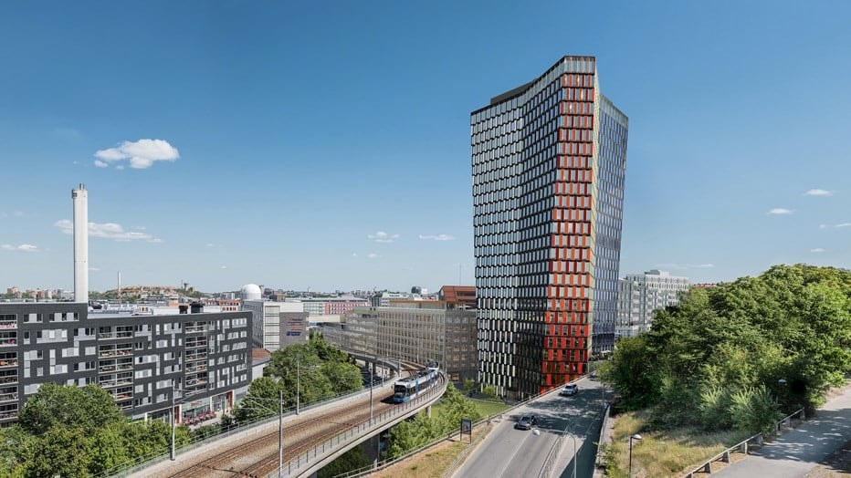 Moderna glas- och stålkontorsbyggnader under en klar blå himmel med starkt solljus.