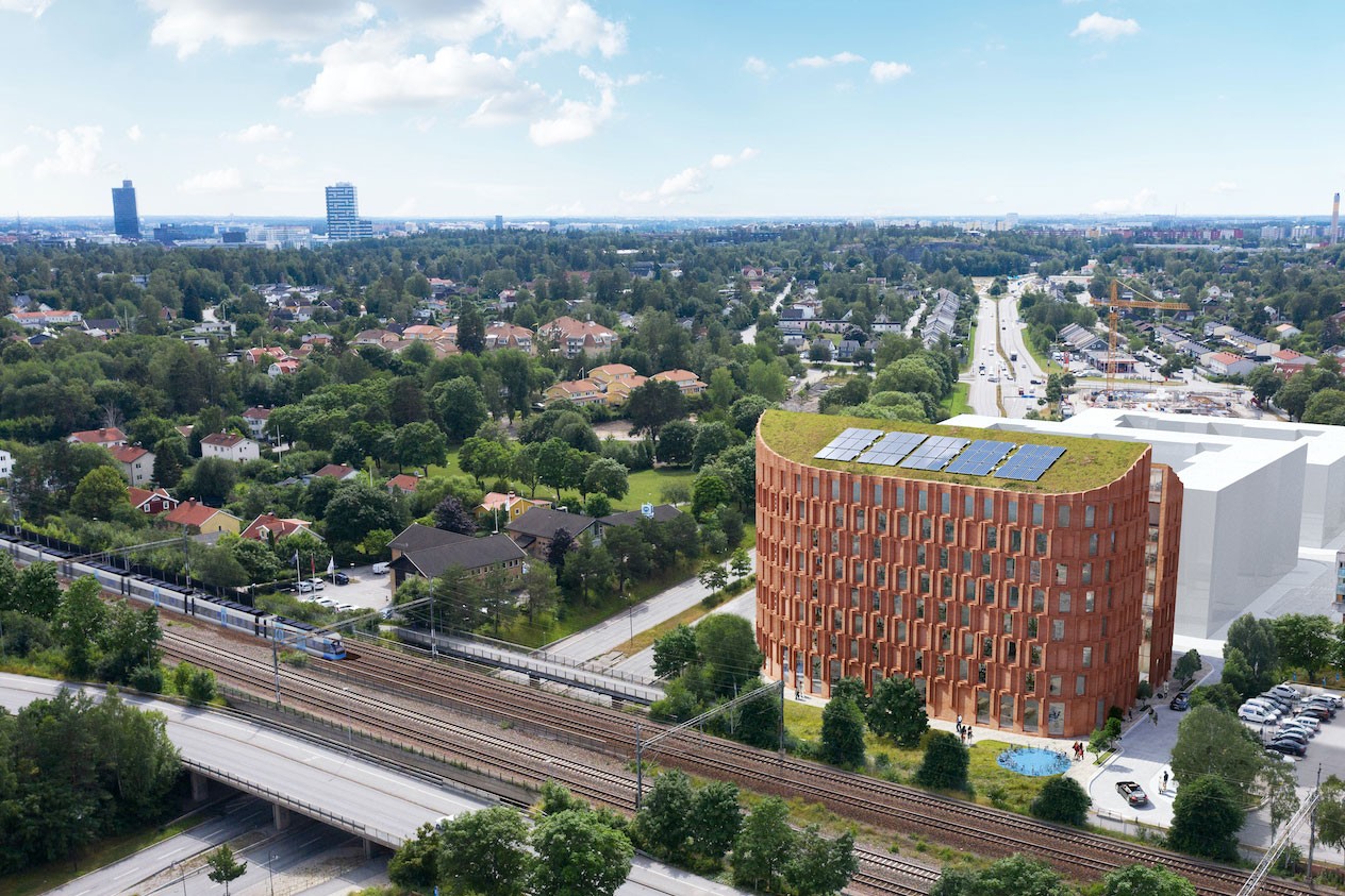 Modern hållbar byggnad med solpaneler i stadsområde Modern tegelbyggnad med solpaneler nära järnväg i en frodig förortsmiljö.