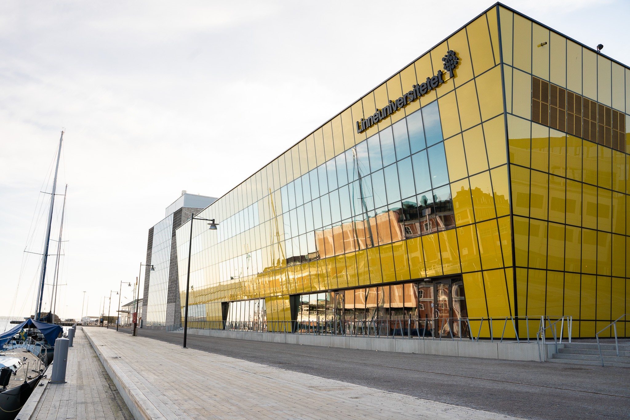 Modern gul glasbyggnad med skylten "Limeinvestietelet" vid en marinabrygga.