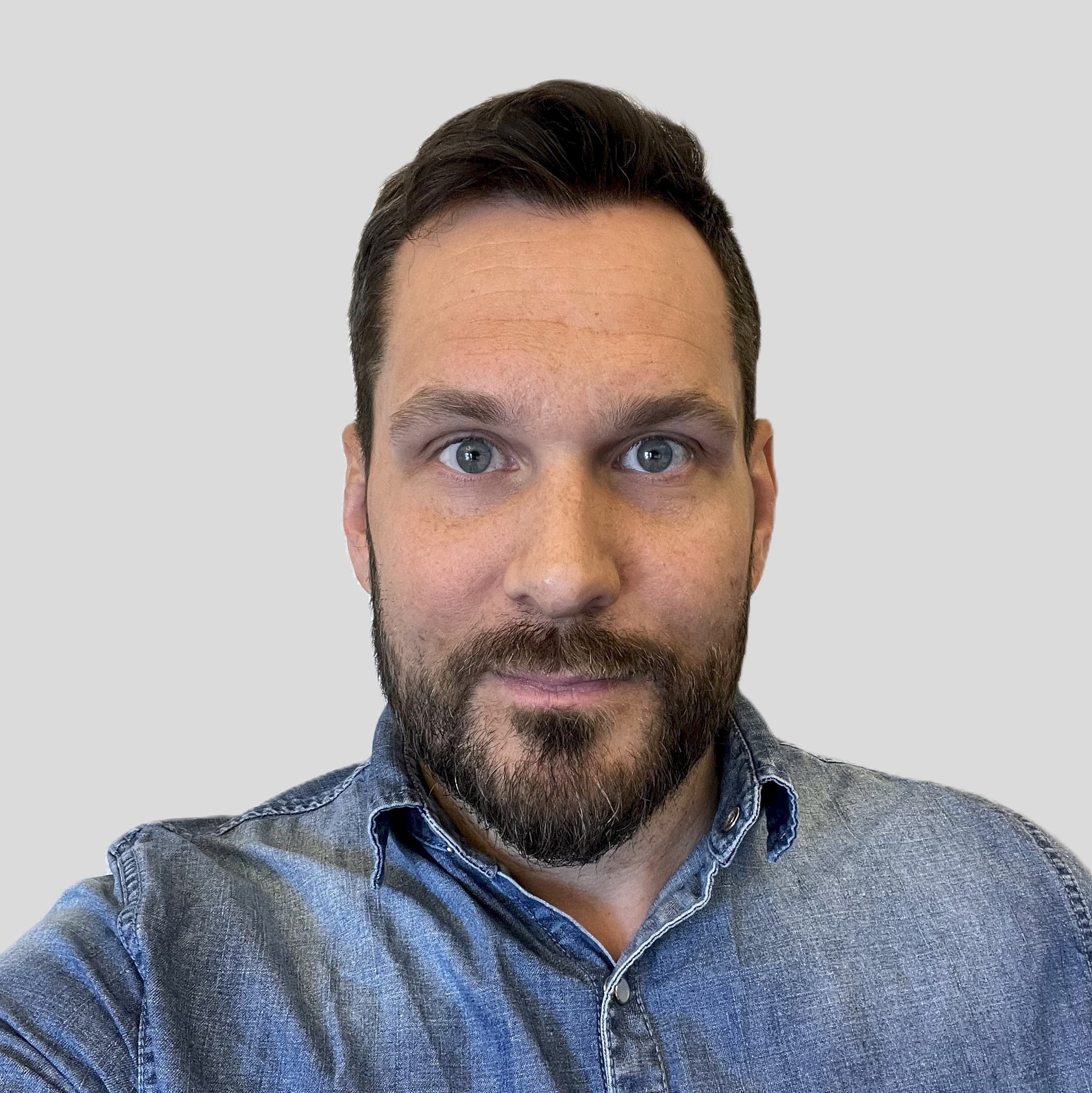Elias Wallgren En person som bär en blå jeansskjorta mot en grå bakgrund.