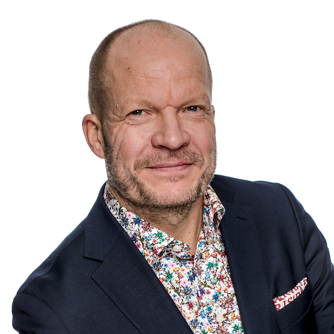 Erik Berntson En person i en mörk kavaj med en färgglad blommig skjorta och matchande bröstnäsduk.