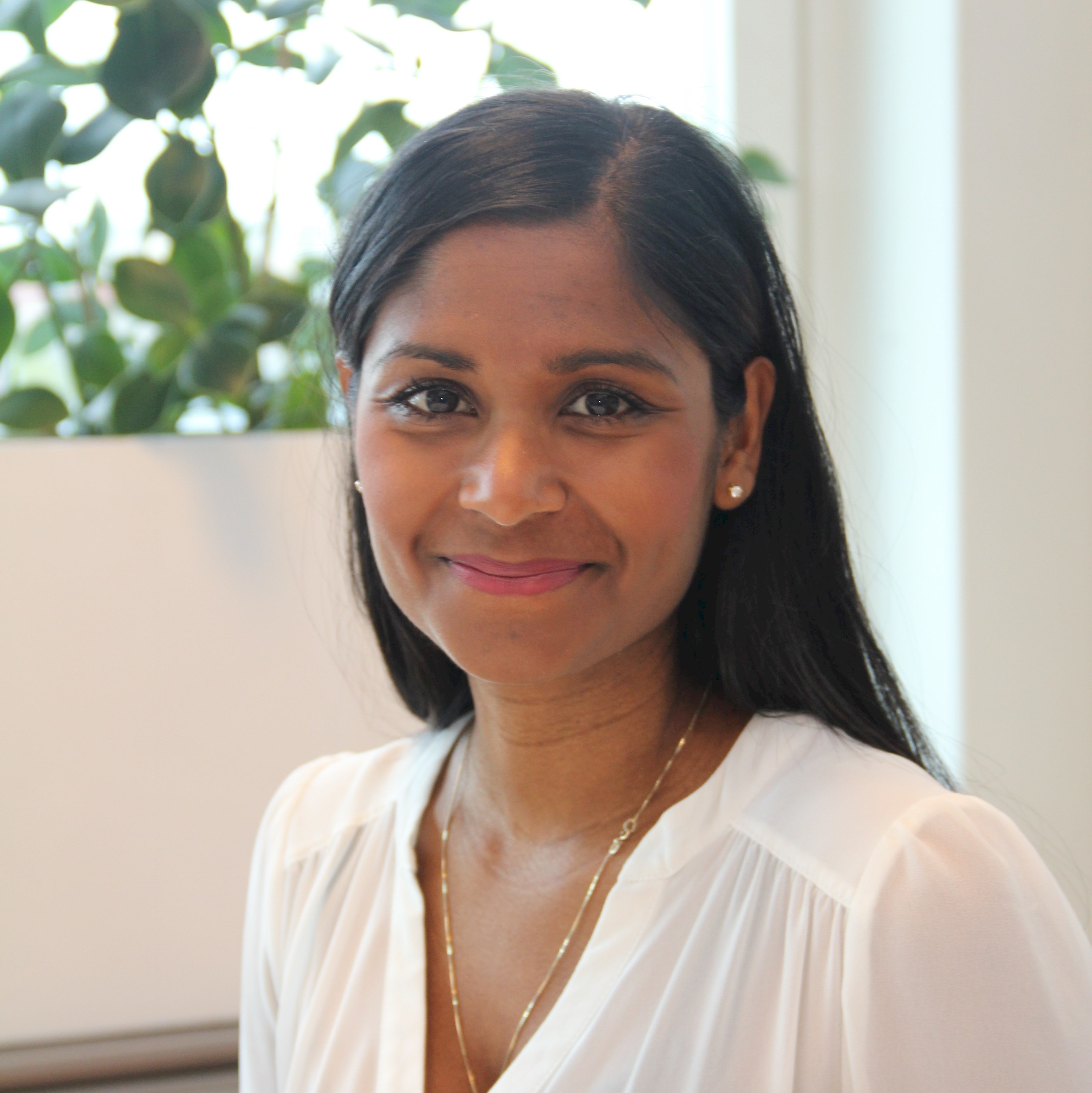 Ida Granqvist Person with long black hair wearing a white blouse and a gold necklace in a bright room.