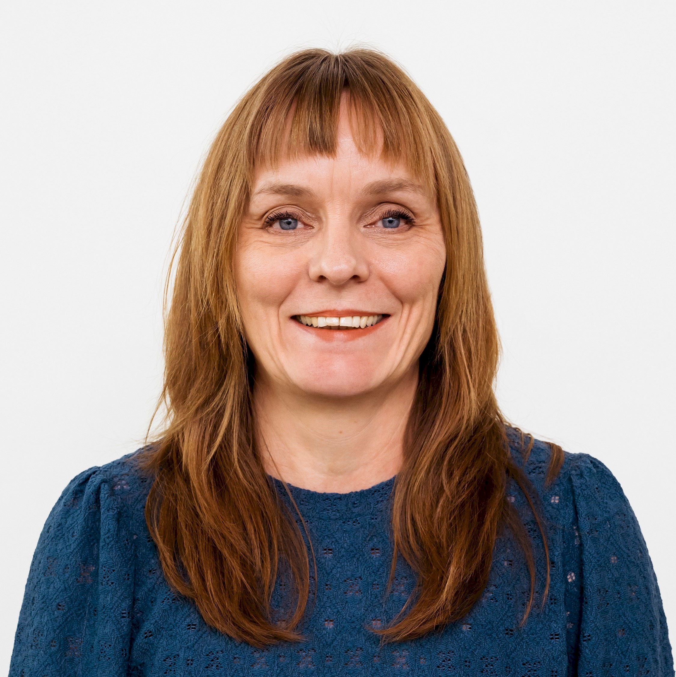 Jeanette Sveder Lundin Person med långt brunt hår som bär en blå texturerad blus mot en vit bakgrund.