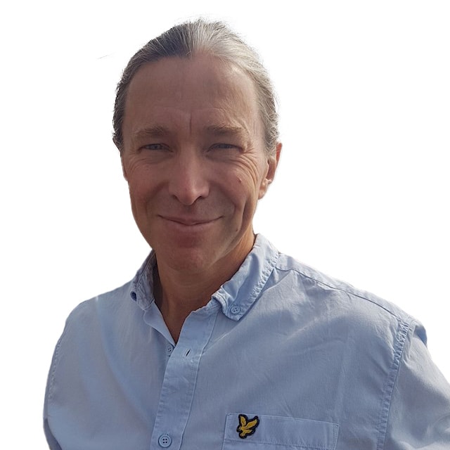 Jesper Blücher En person som bär en ljusblå skjorta med ett gult fågelemblem på fickan mot en vit bakgrund.
