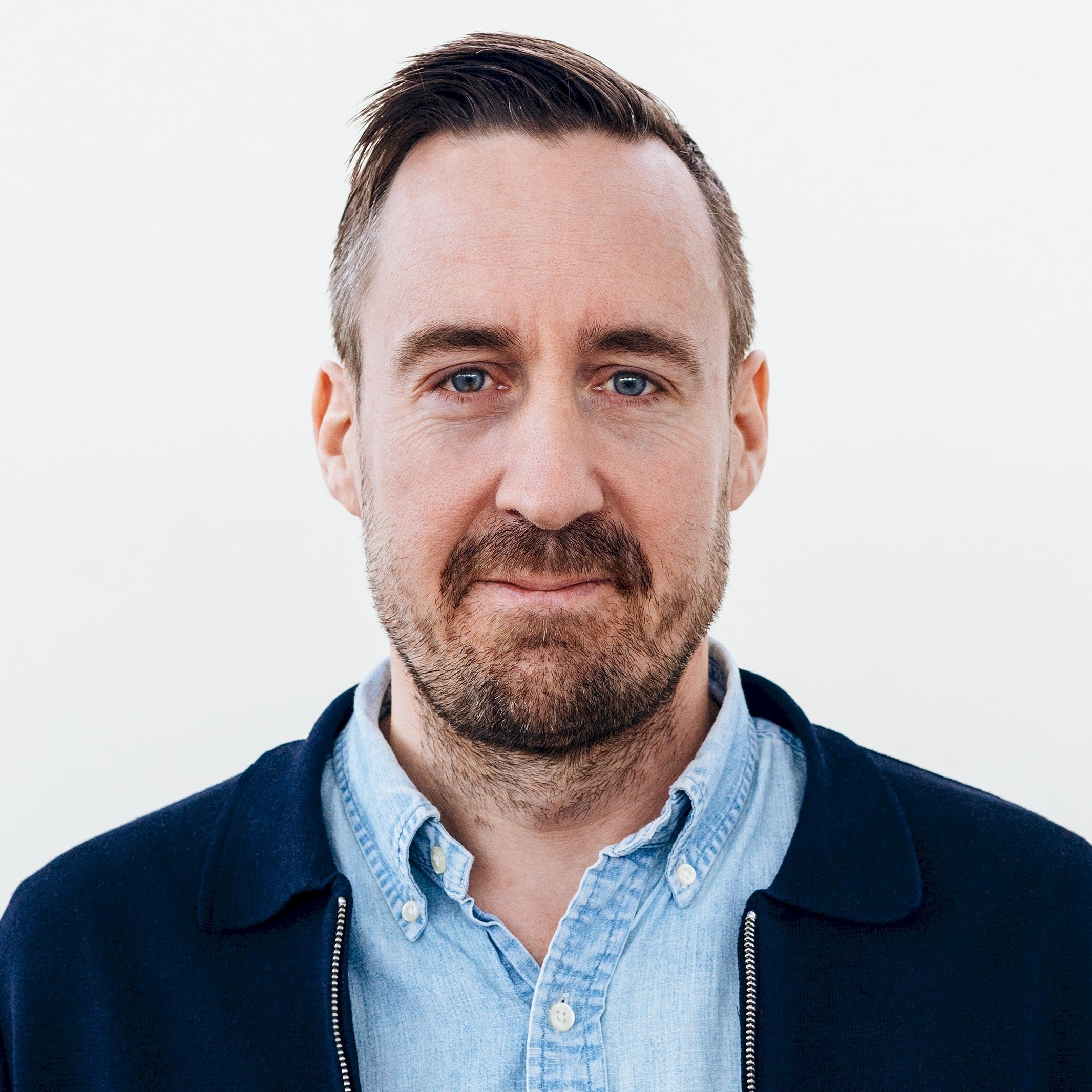 Magnus Christiansen Person med mörkt hår och skägg i mörk kavaj med ljusblå skjorta.