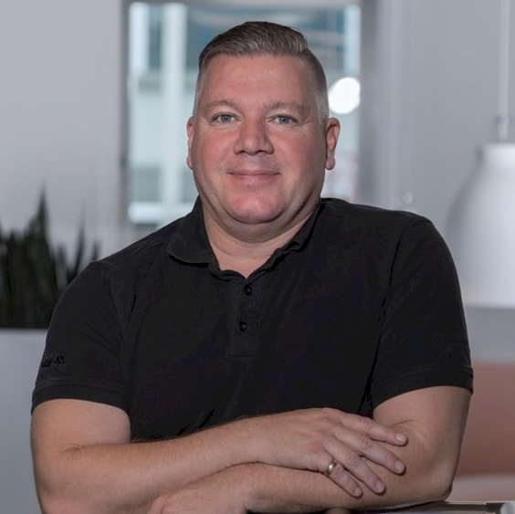 Magnus Samuelsson Professionell man i svart skjorta som sitter vid ett skrivbord.
