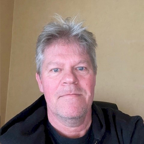 Nicklas Persson En person med grått hår som bär en svart hoodie sitter framför en beige vägg.