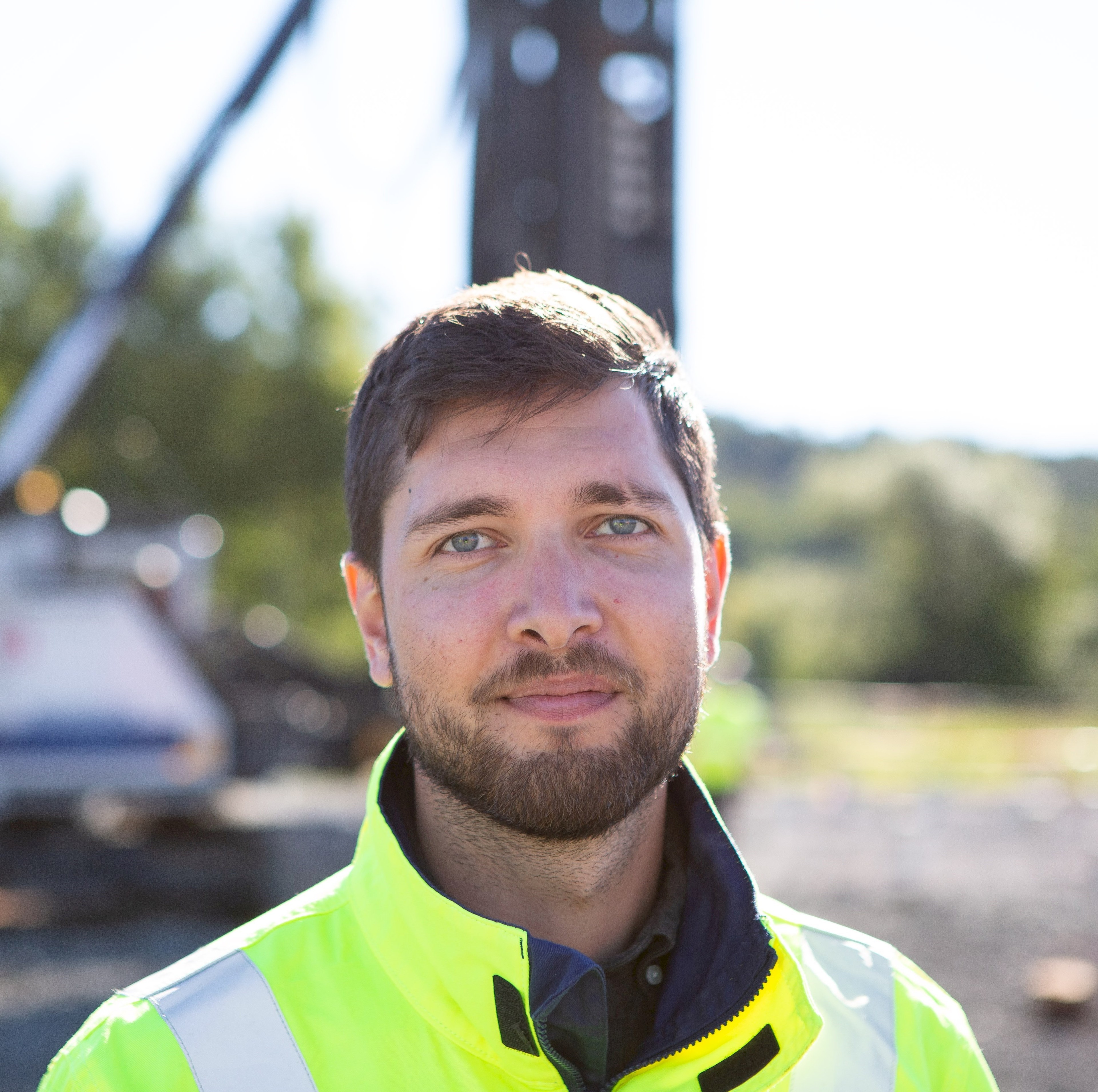 Olle Brandt A person wearing a high-visibility jacket stands at a construction site with machines in the background.