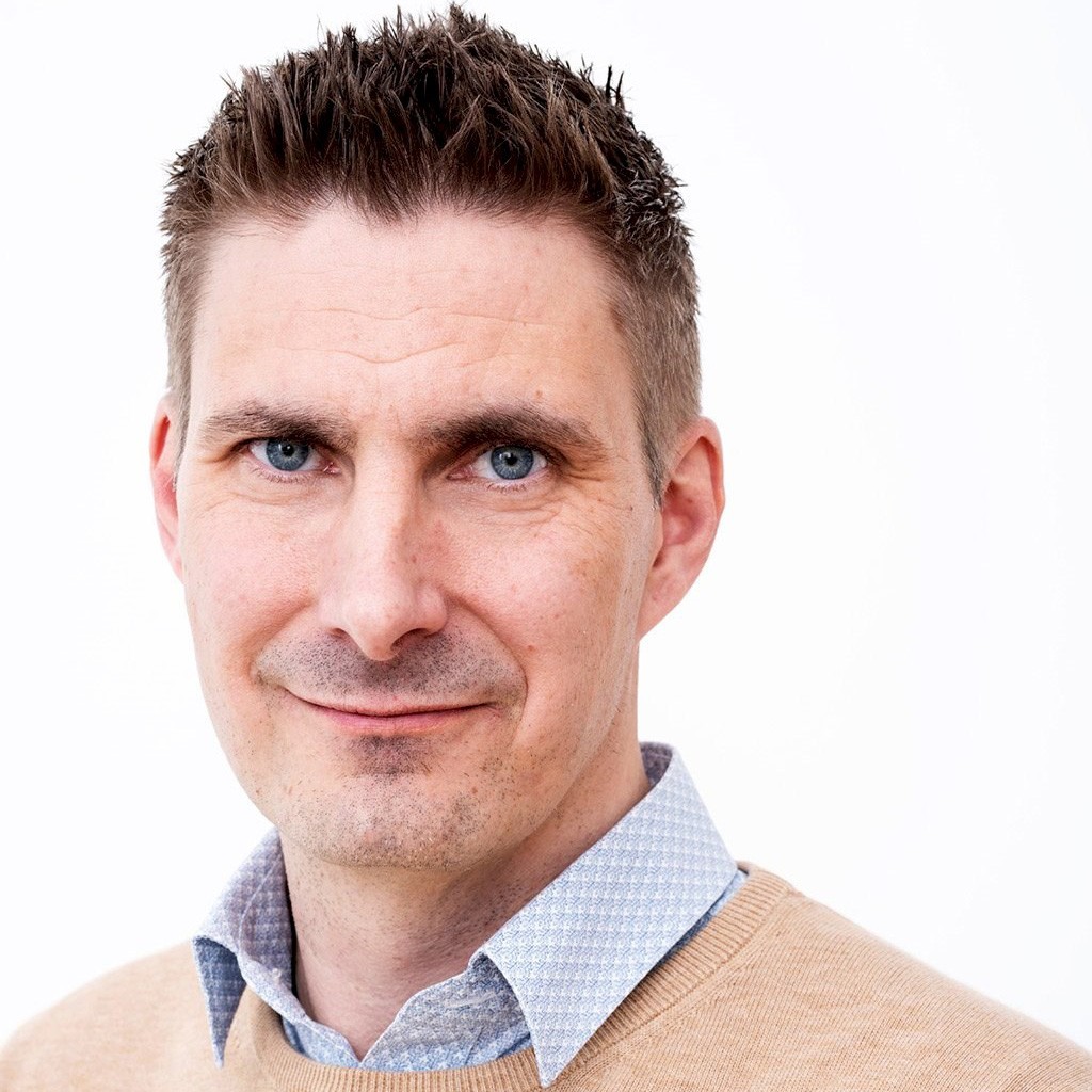 Peter Halling Person med kort brunt hår som bär en blå skjorta och en beige tröja.
