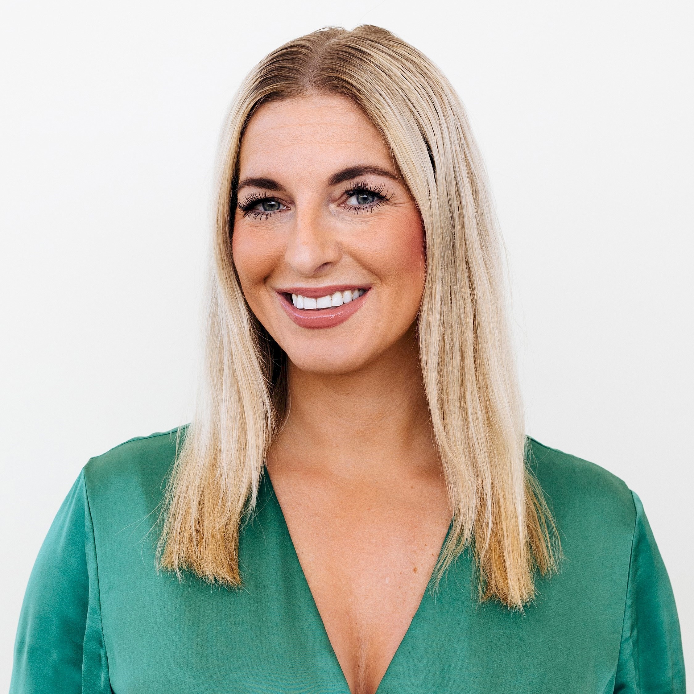 Sophia Granswed Baat Kvinna med rakt blont hår som bär en grön V-ringad blus mot en vit bakgrund.