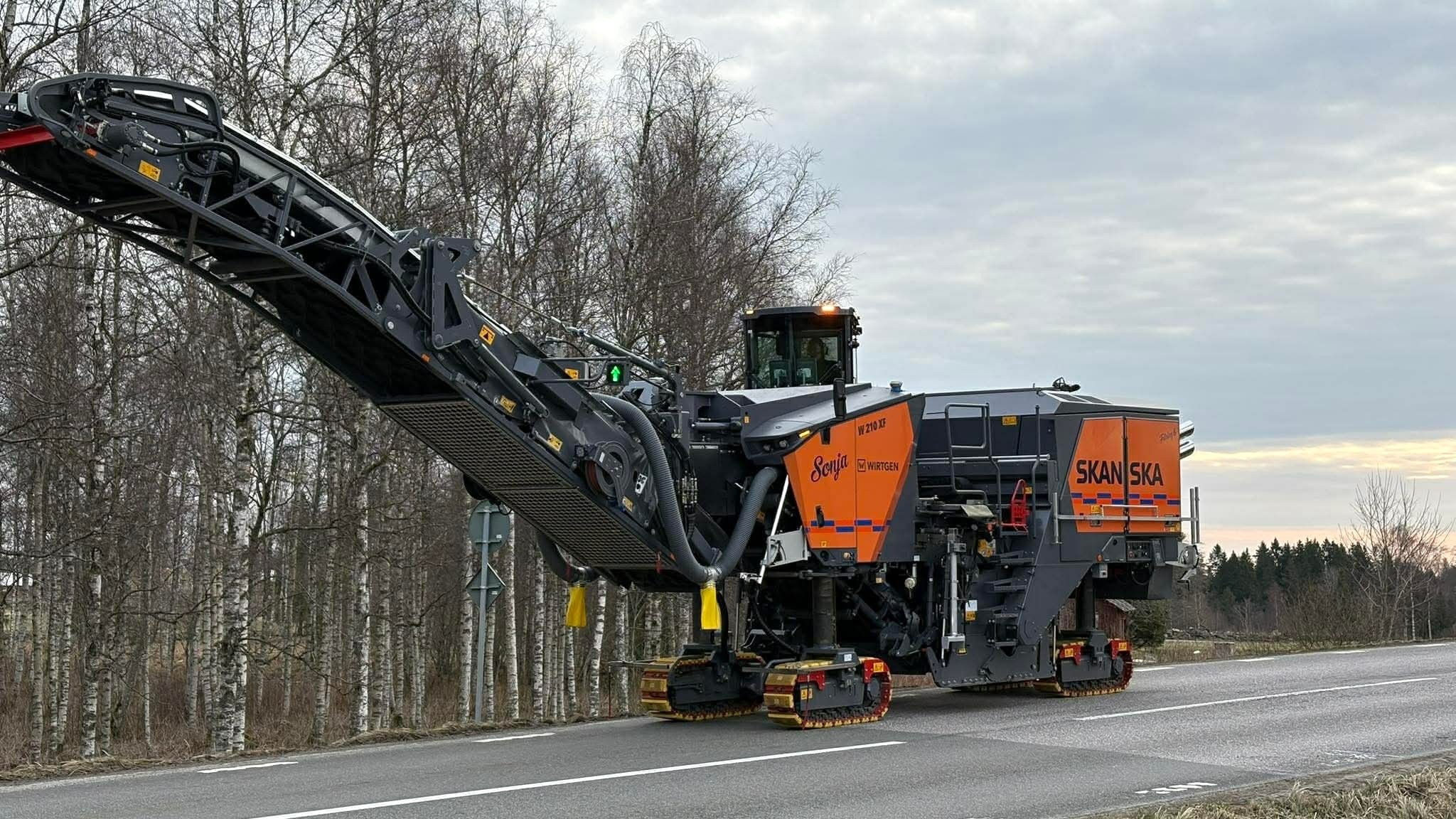 En fräsmaskin står på en asfalterad väg.