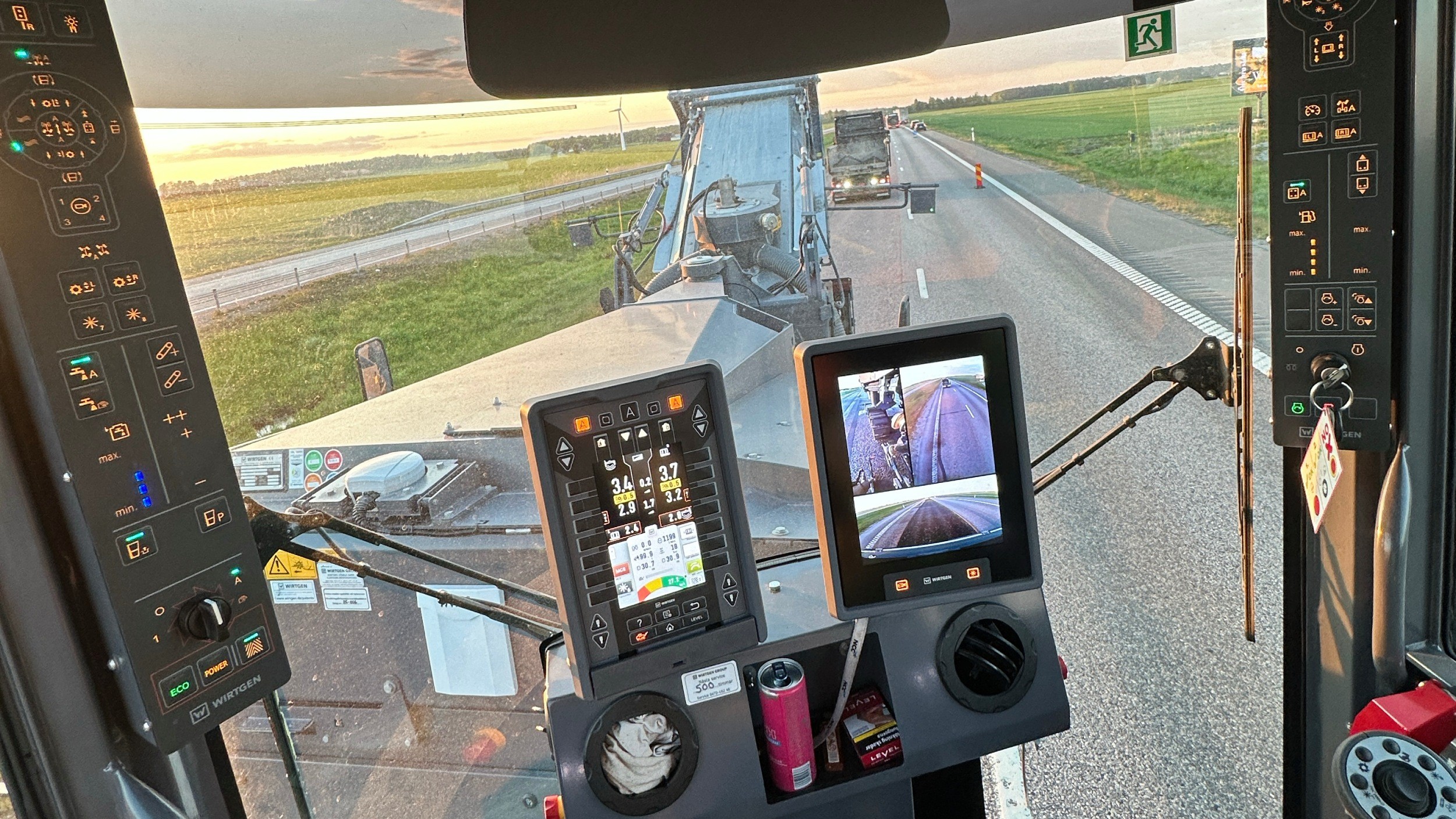 Utsikt från insidan av en modern traktorkabin som visar reglage, skärmar och en fältväg framför.
