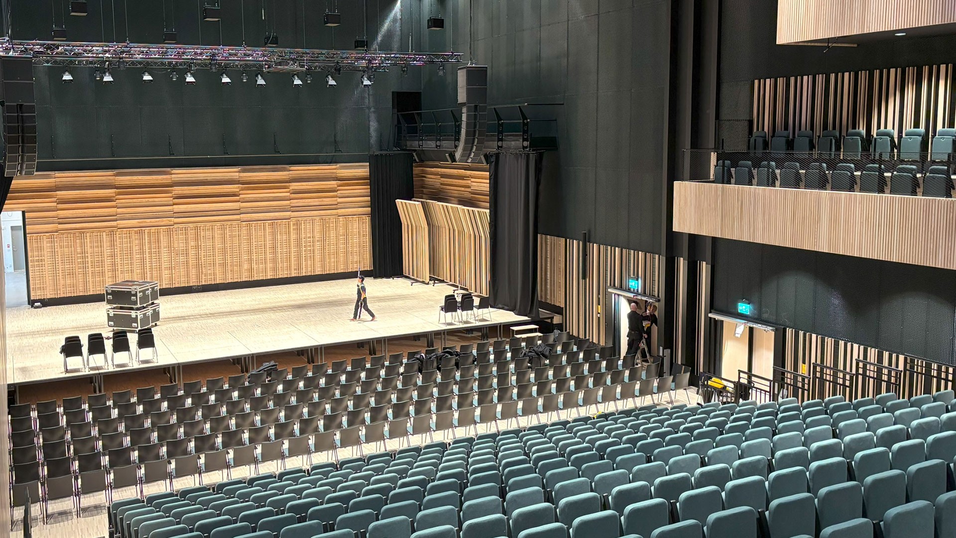 Modern tom auditorium med nivåindelade sittplatser och en stor scen redo för evenemang.