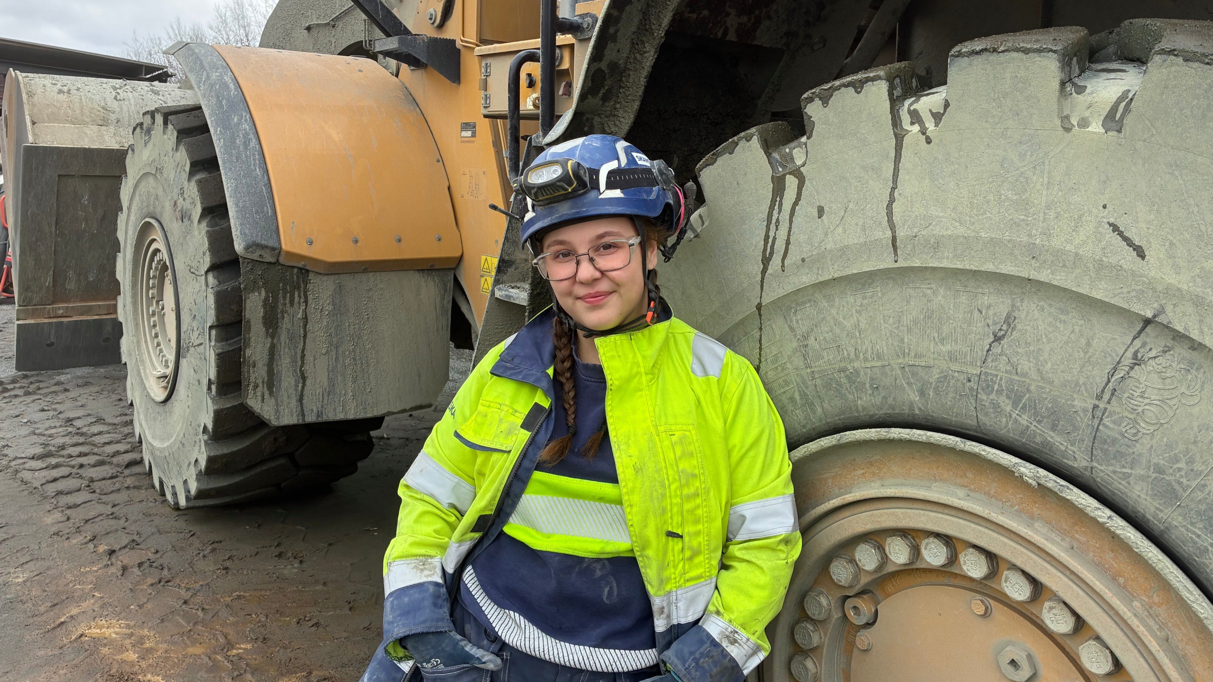 En ung kvinnlig medarbetare i bergtäkten i Önnestad står framför en dumper.