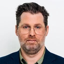 Joakim Åkesson Person with short dark hair wearing a navy blue blazer and green shirt against a white background.