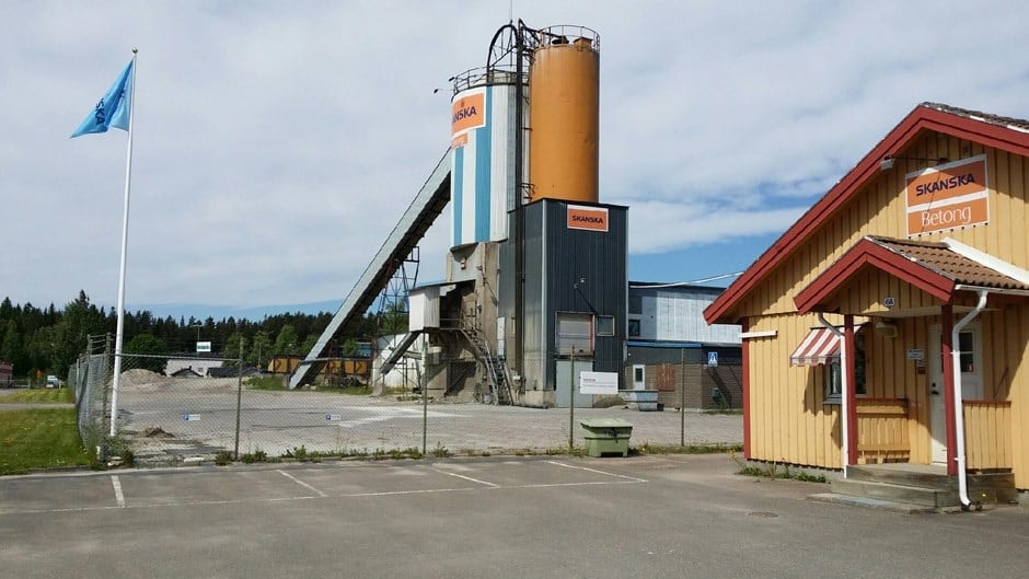 Skanska Concrete Plant with Storage Silos and Office Building Industriell cementfabrik med silos och en gul kontorsbyggnad under en blå himmel.
