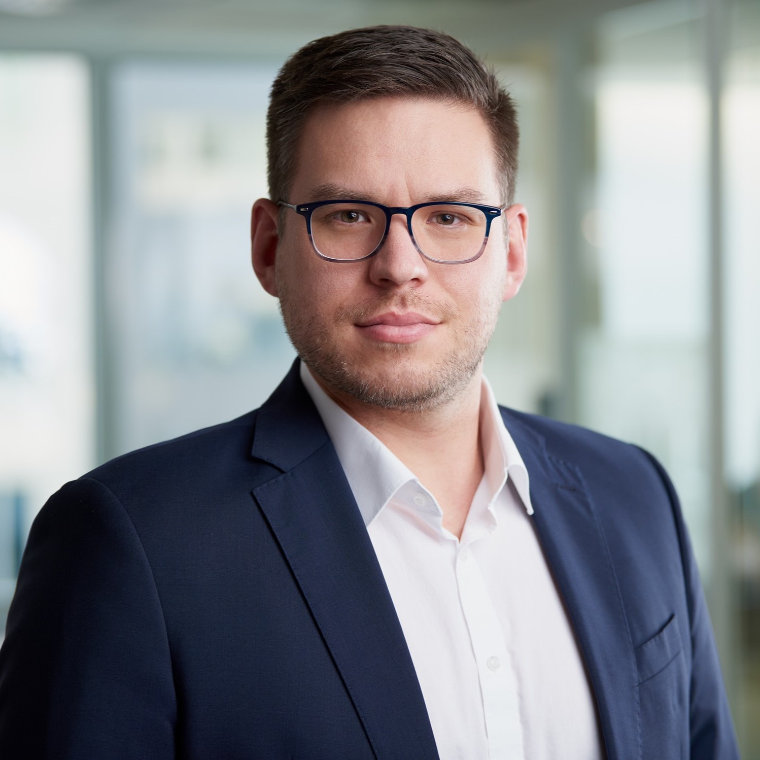 Professional man in navy suit and white shirt in modern office András Ábrahám