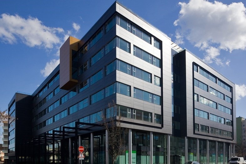 Green House Modern office building with glass facade and angular design under a clear blue sky.