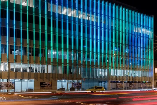 Nordic Light Uno & Duo Modern building with vibrant blue and green illuminated facade at night, with street traffic below.