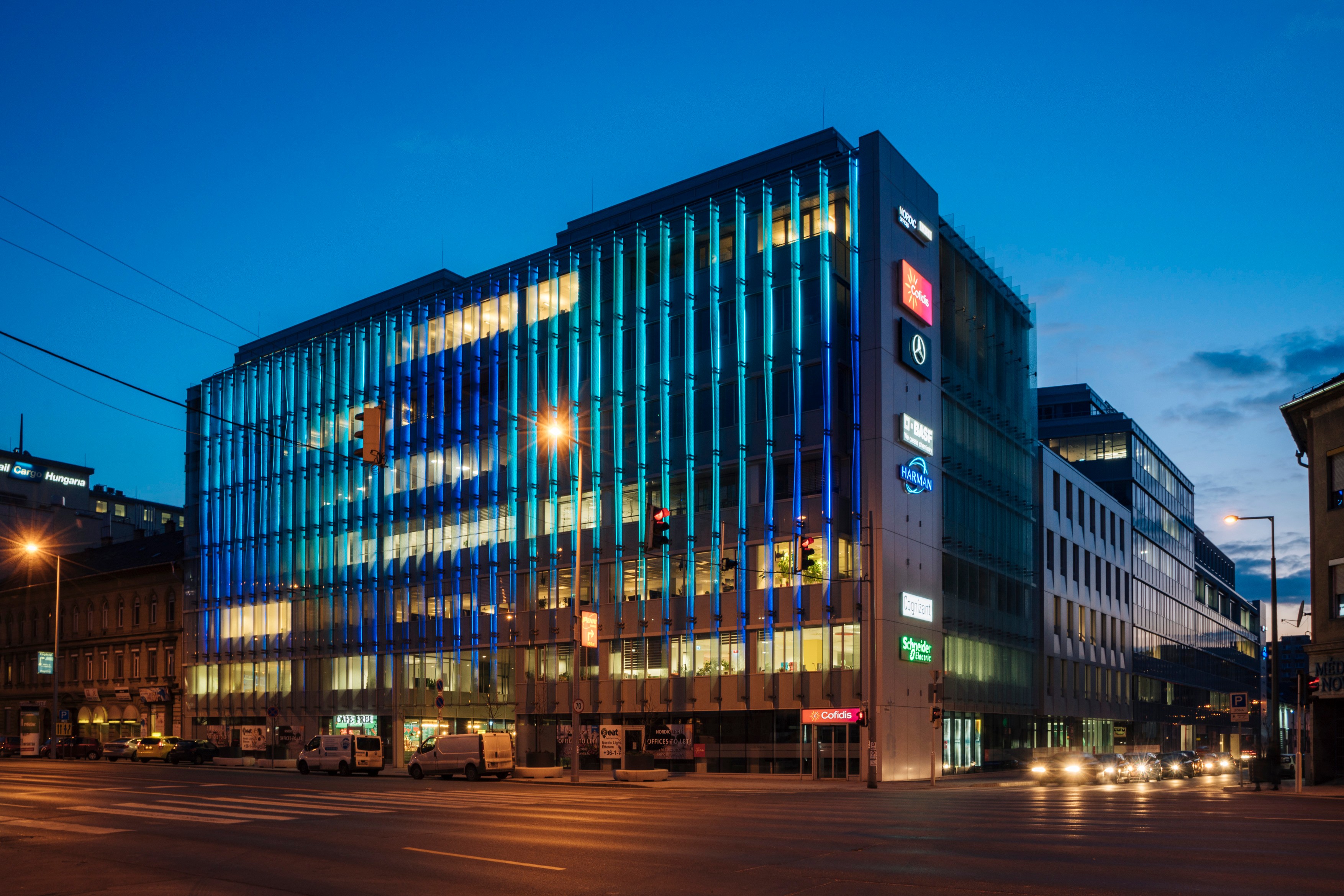Nordic Light Modern office building with illuminated glass facade at dusk on a city street corner.
