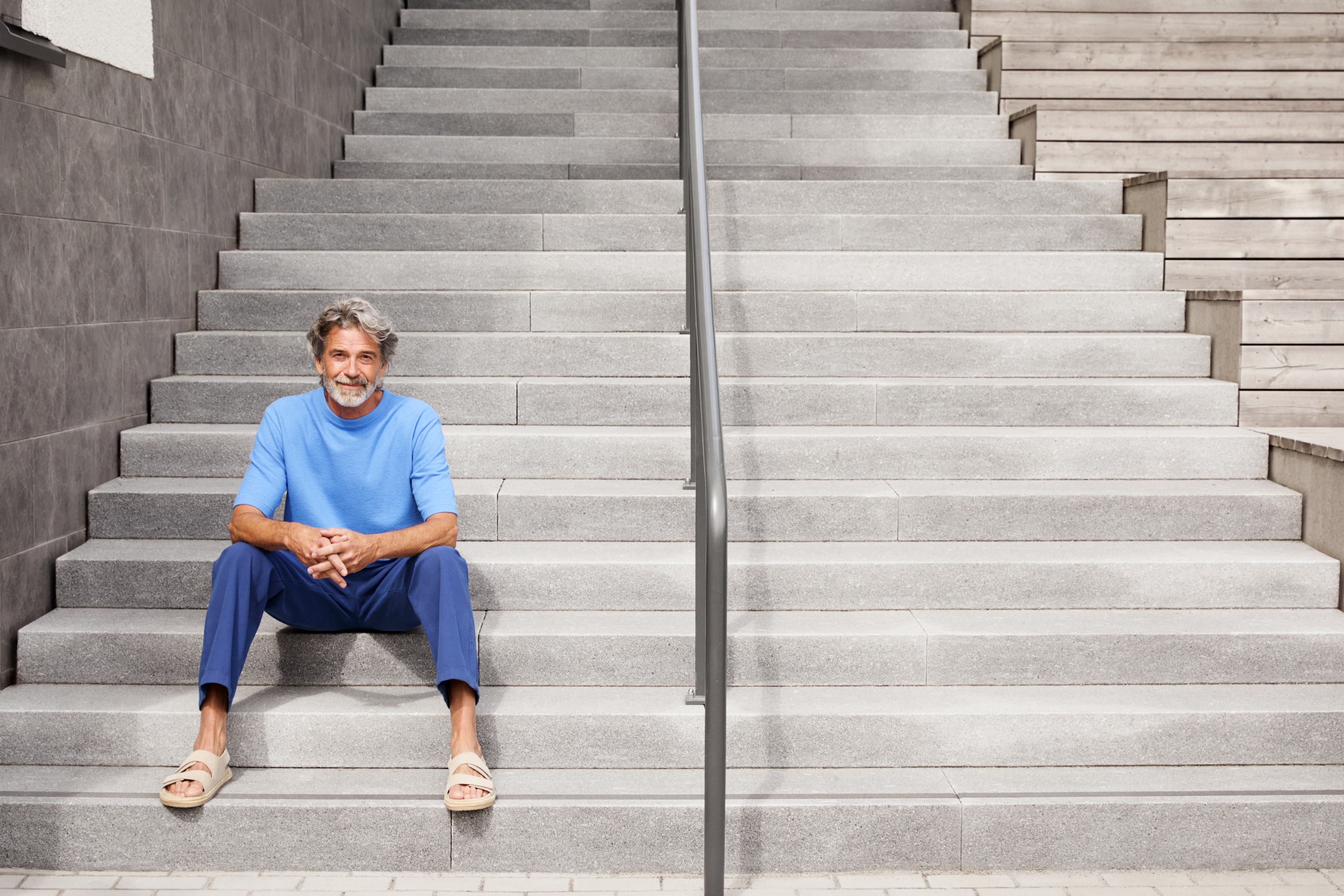 Skanska's culture of openness Man in blue shirt sitting on wide outdoor concrete stairs with metal handrail.