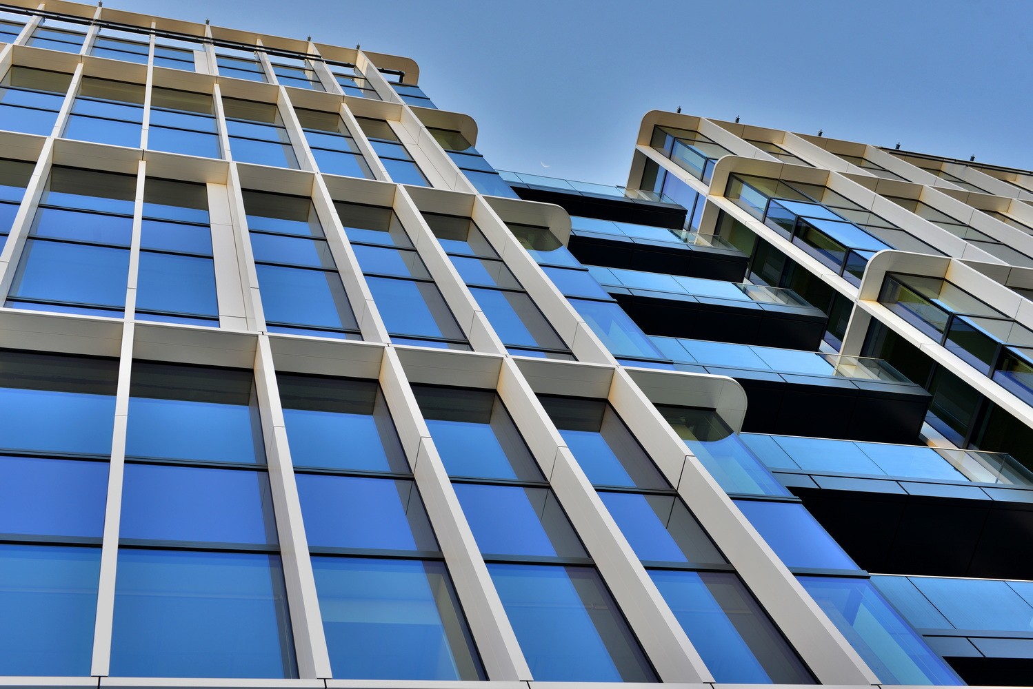 H₂Offices Phase 1 Modern glass office building facade with reflective windows against a clear blue sky.
