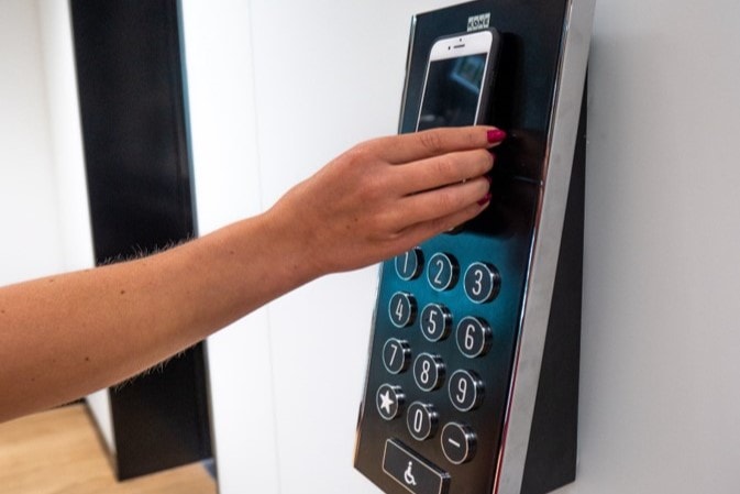 A person uses a smartphone to access a keypad security system, illustrating modern technology use.