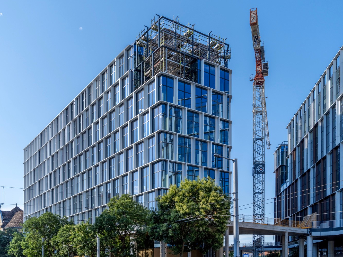 Modern concrete building under construction with scaffolding and clear blue sky.