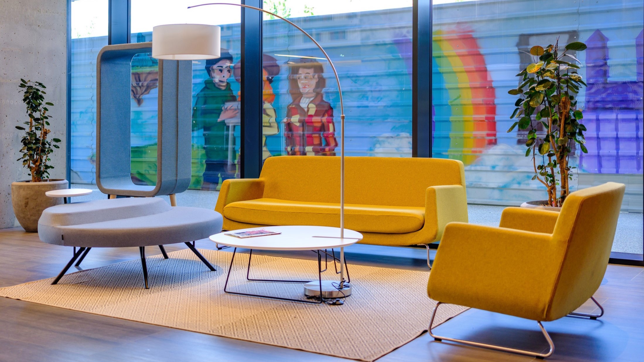Campus 6.3 reception Modern lounge with vibrant yellow seating, sleek furniture, and colorful wall mural.