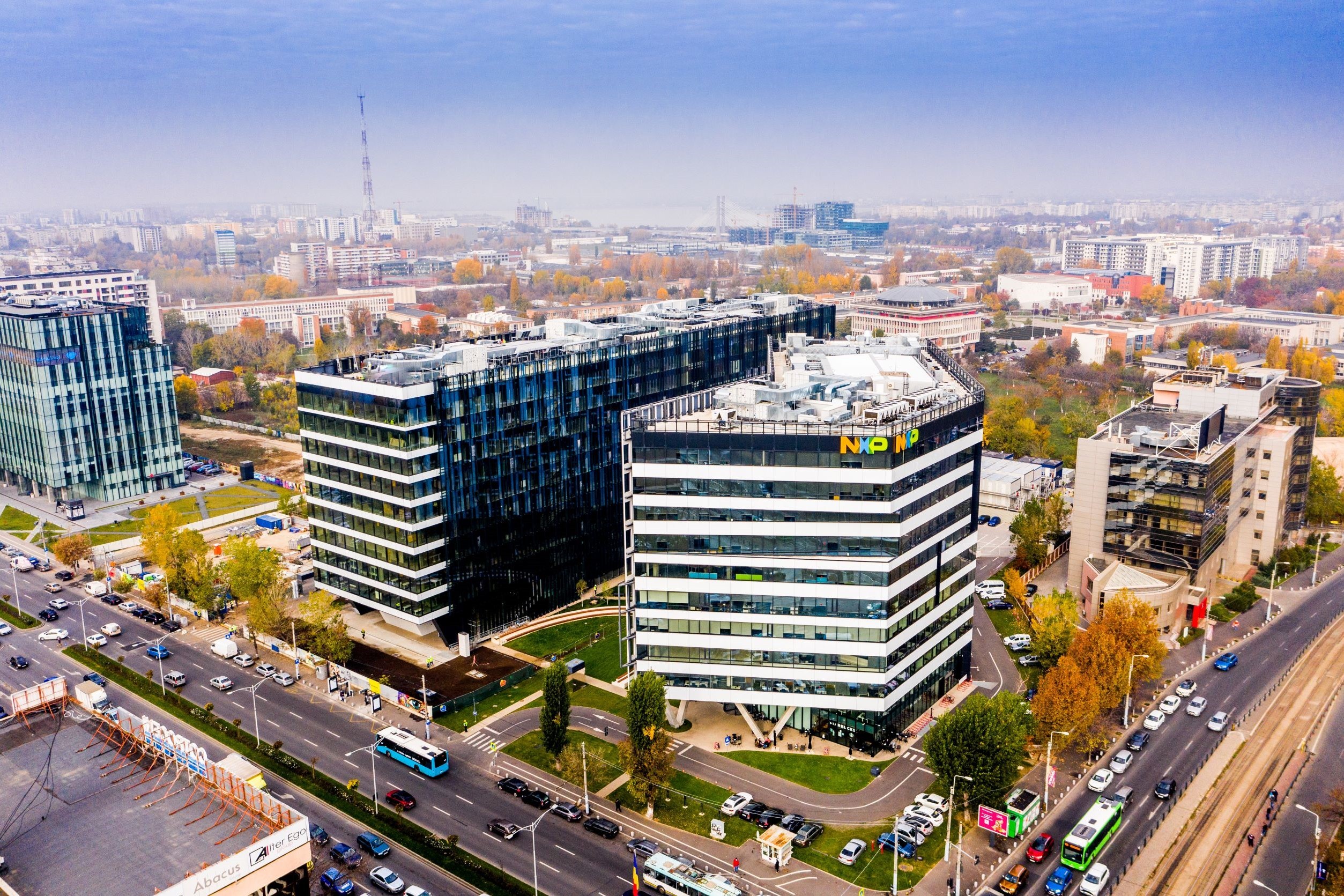 Campus 6 Aerial view of modern office buildings in a bustling cityscape, surrounded by roads and autumn trees.