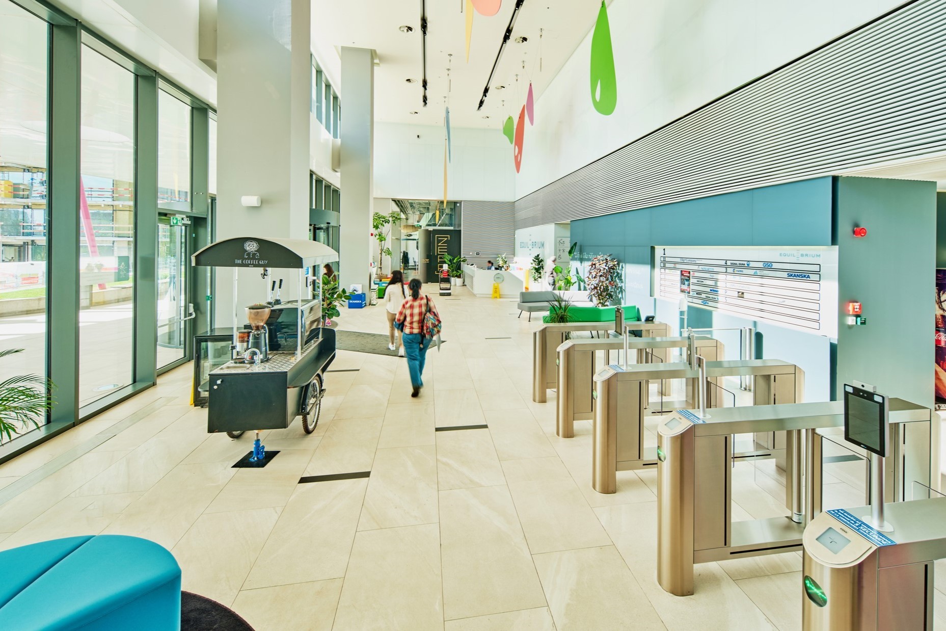 Equilibrium 1 reception Modern office lobby with security gates, colorful decor, and a small coffee cart.