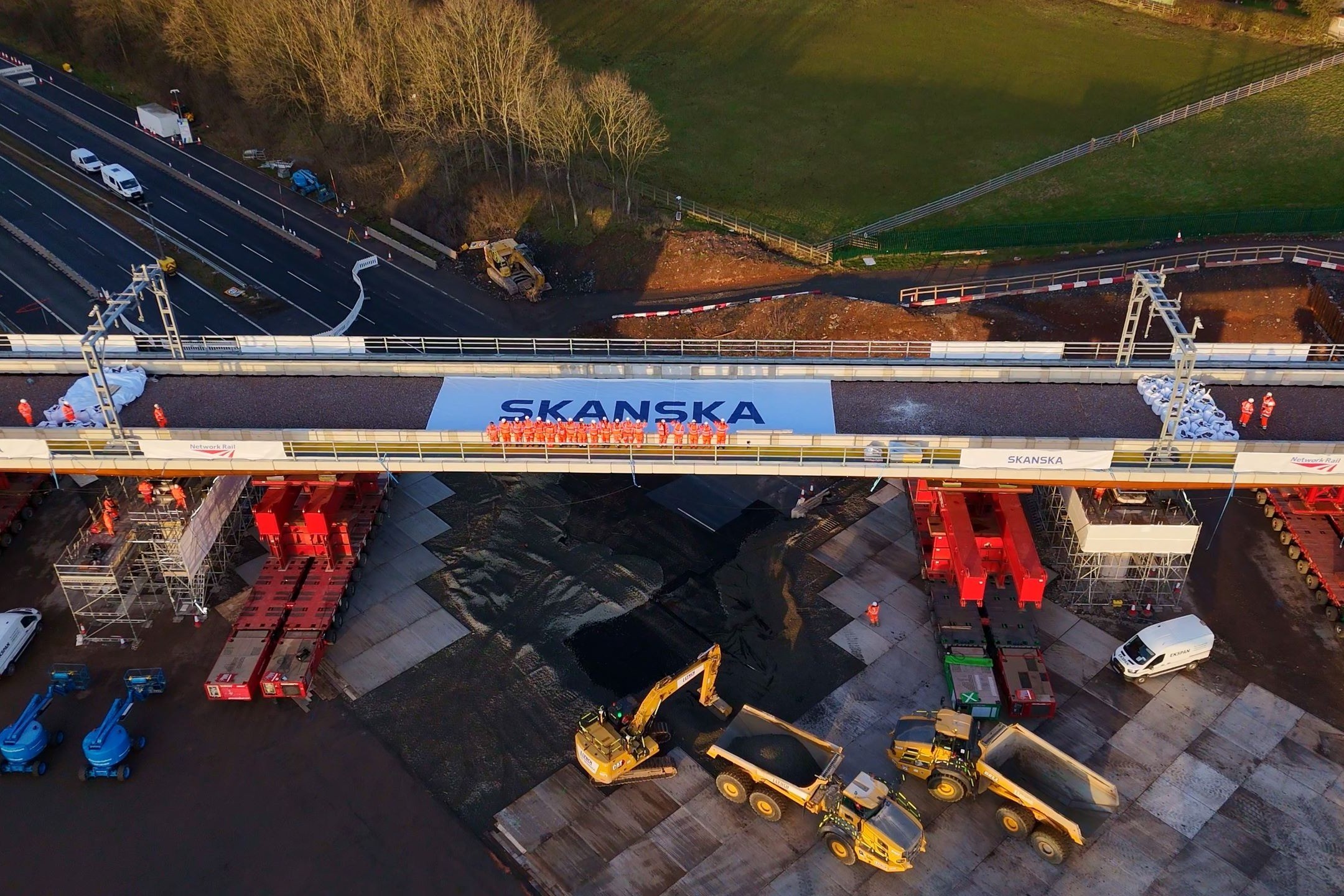 Bridge Construction by Skanska: Engineering in Action Aerial view of construction site with heavy machinery, workers, and a bridge marked "Skanska."