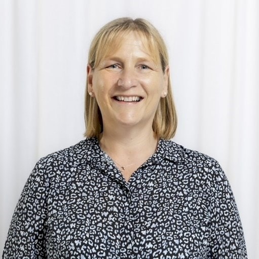 Woman in Blouse with Blonde Hair on White Background Woman wearing a black and white patterned blouse standing against a white curtain background.