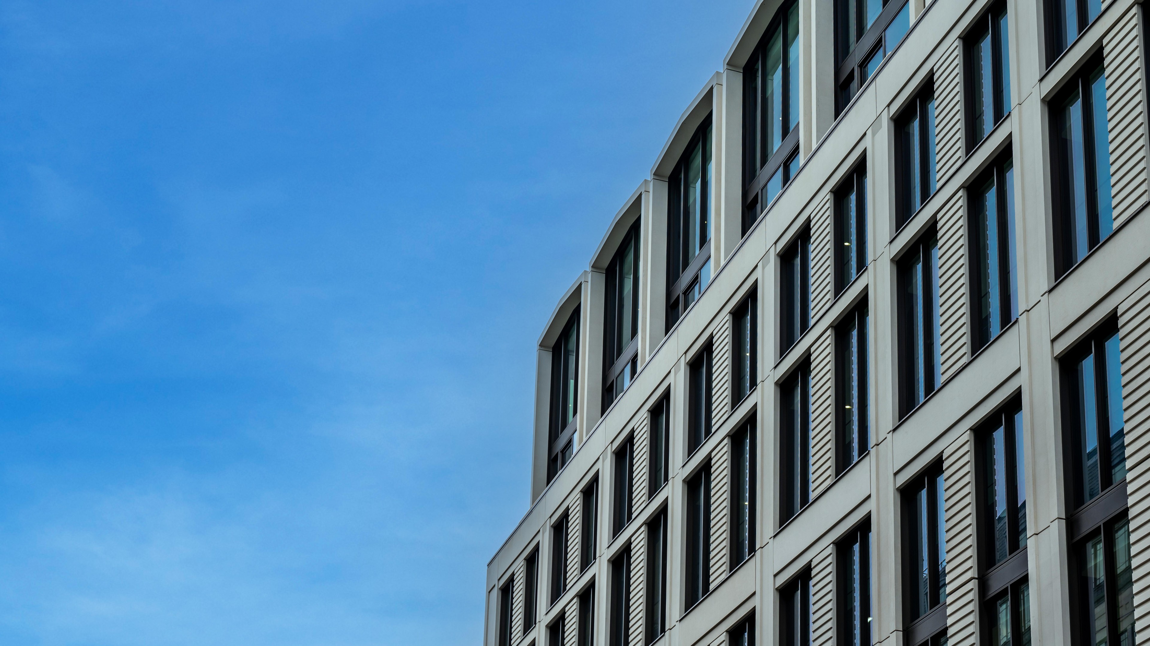 Modern office building with reflective glass windows against a clear blue sky.