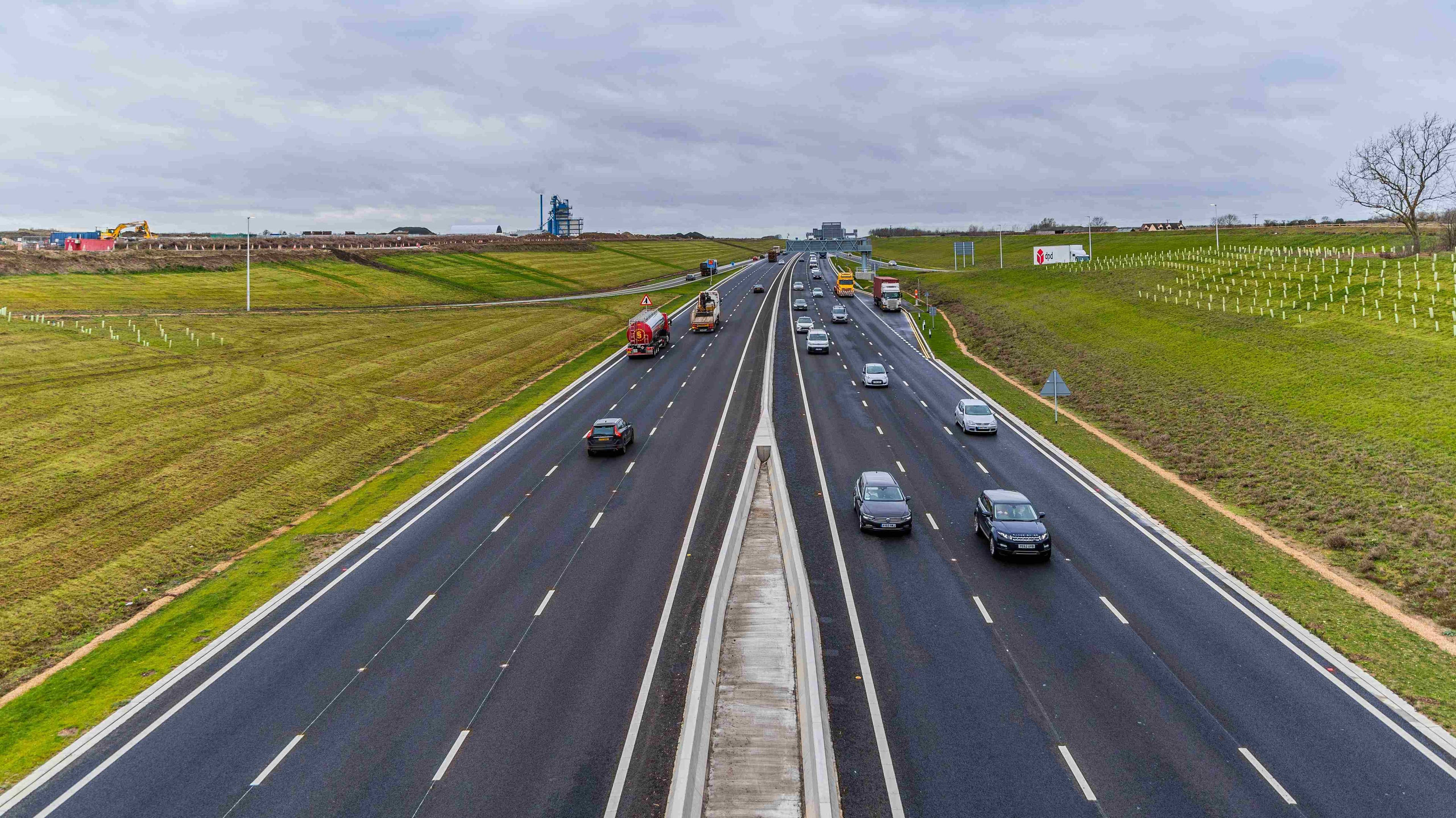 Smooth Traffic Flow on Modern Multi-Lane Highway in Countryside Aerial view of a busy highway with multiple lanes and cars under a cloudy sky.