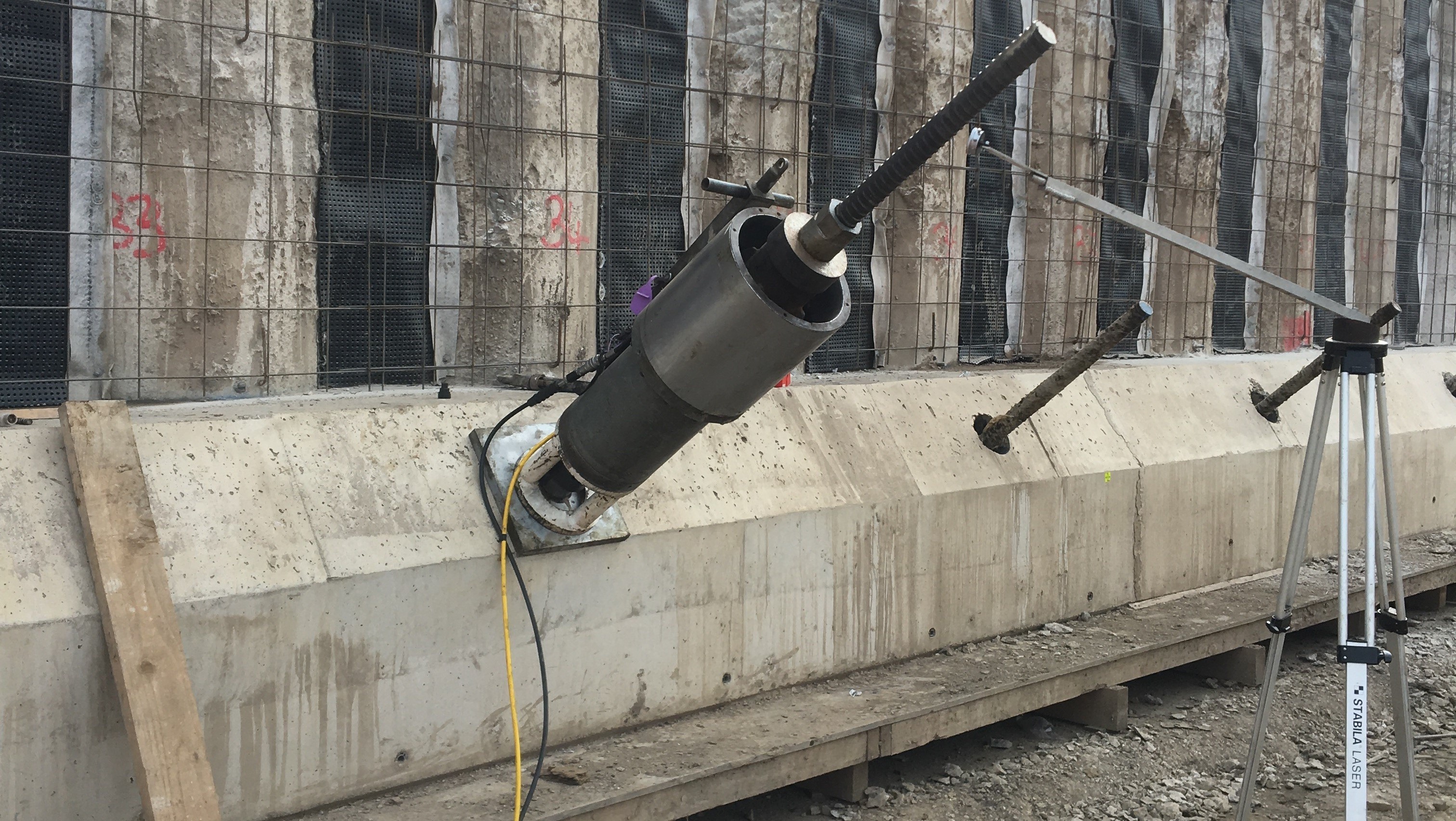 Concrete Wall Testing Equipment Mounted at Construction Site Concrete wall drilling machine mounted on a tripod for construction site work.