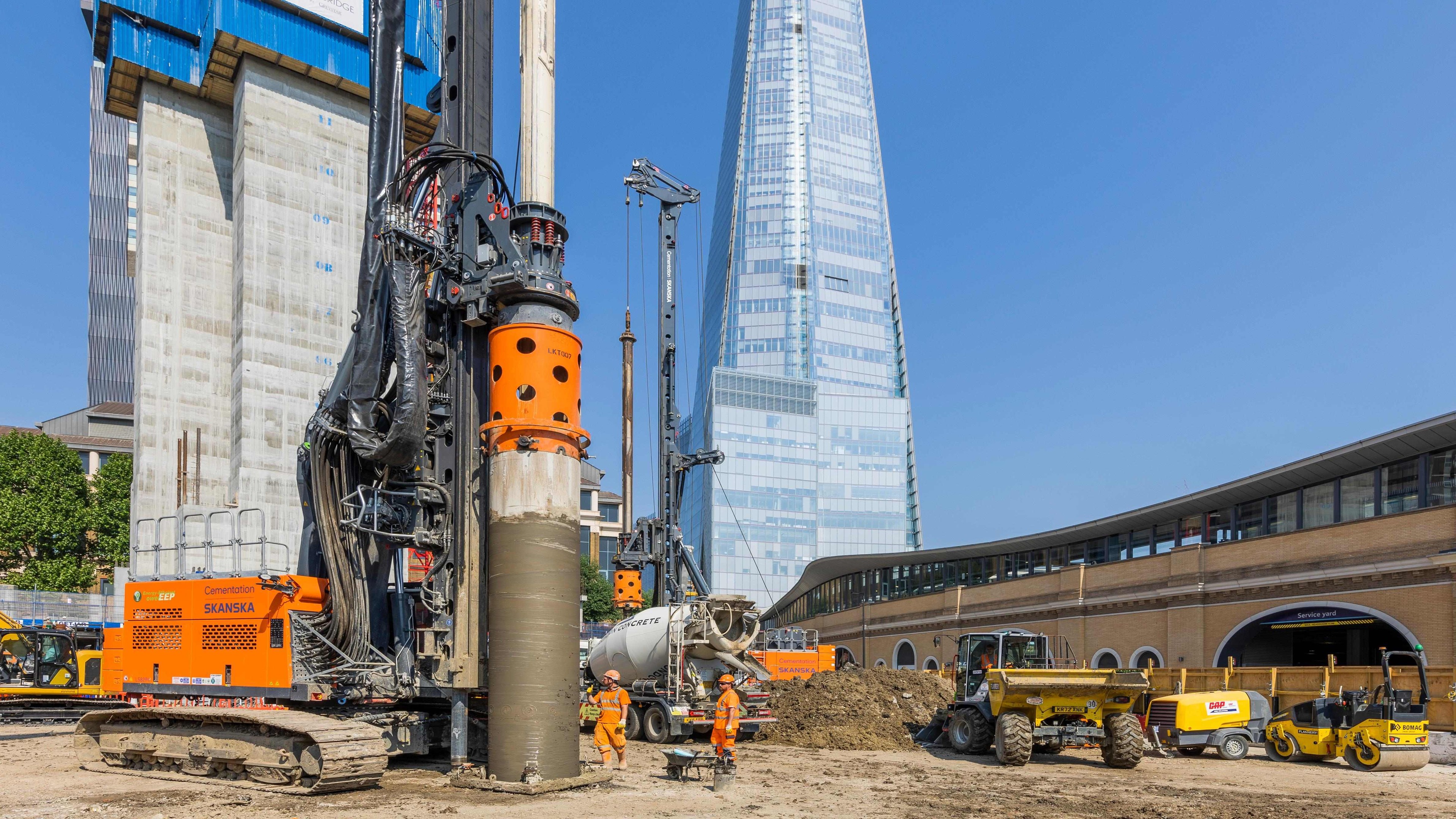 Urban construction site with heavy machinery and skyscraper Construction site with heavy drilling machinery and modern skyscraper in the background.