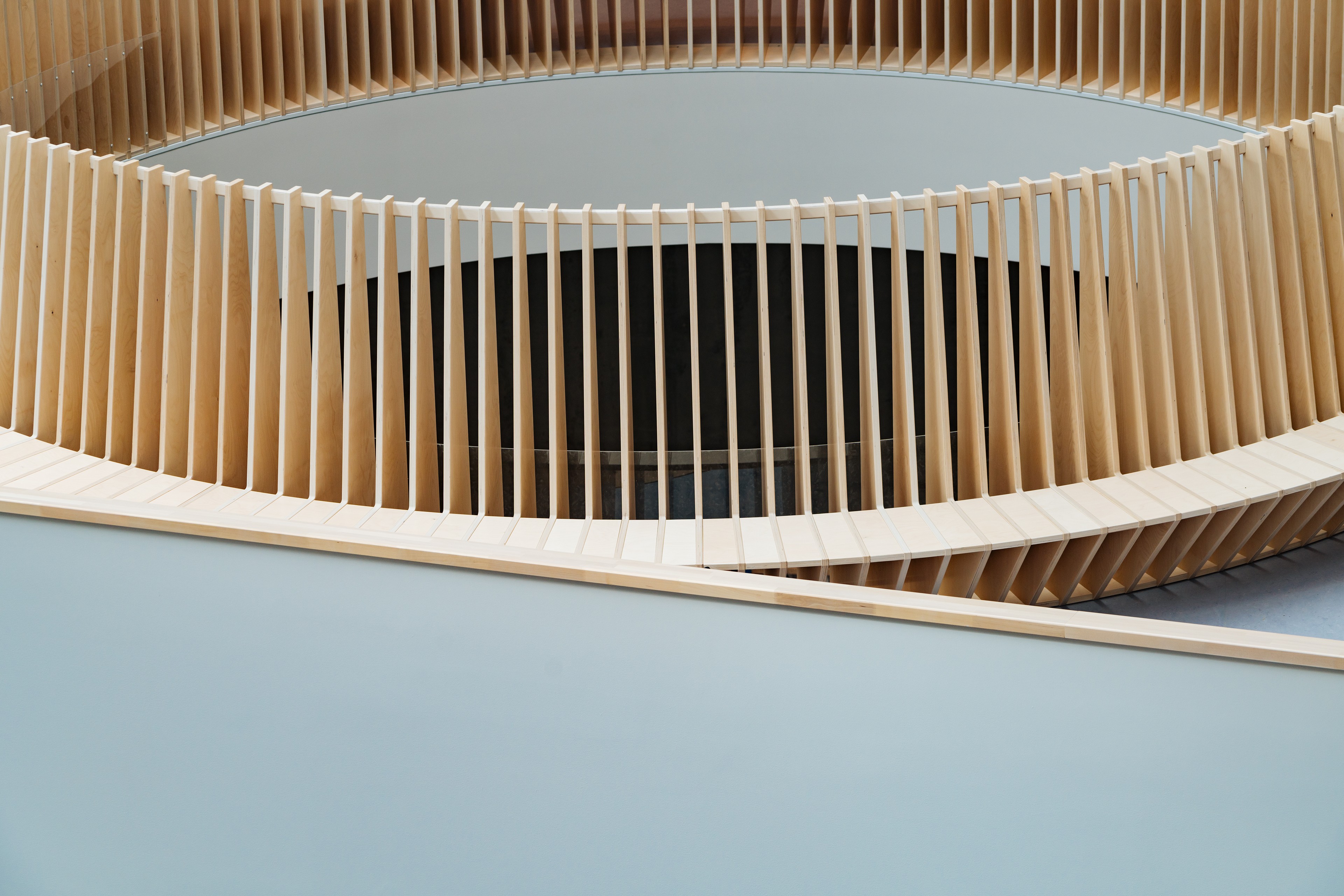 Modern spiral staircase with wooden vertical slats and minimalist design details.