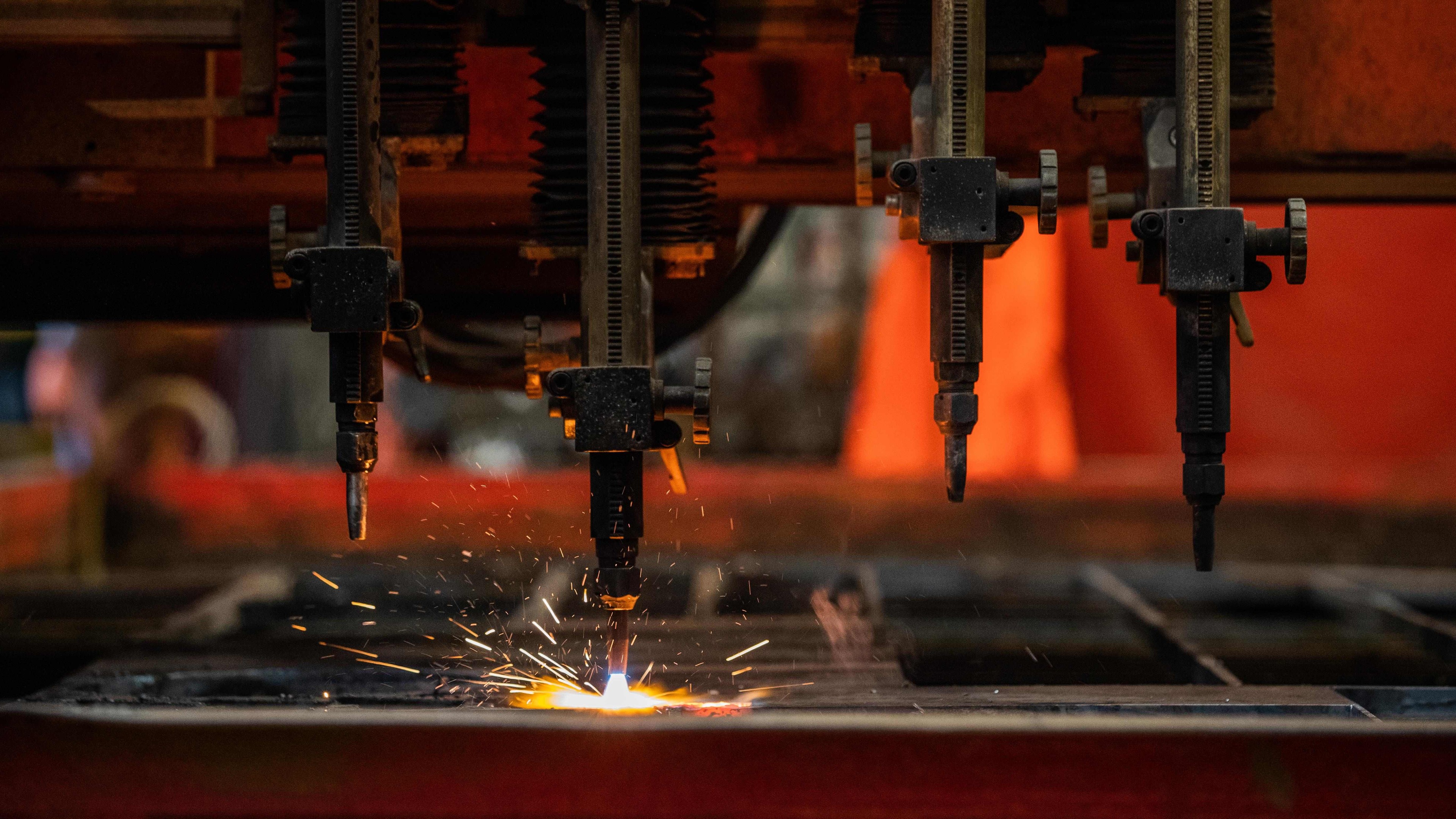 Industrial CNC machine cutting metal with bright sparks in a manufacturing workshop.