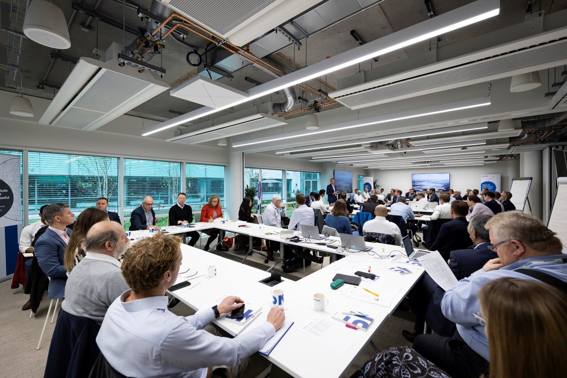 Corporate business meeting with diverse professionals in office Business meeting in modern office with diverse professionals discussing around tables.